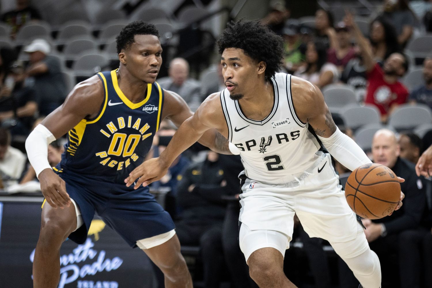 NBA players from the Spurs and Pacers compete for possession during a professional basketball game.