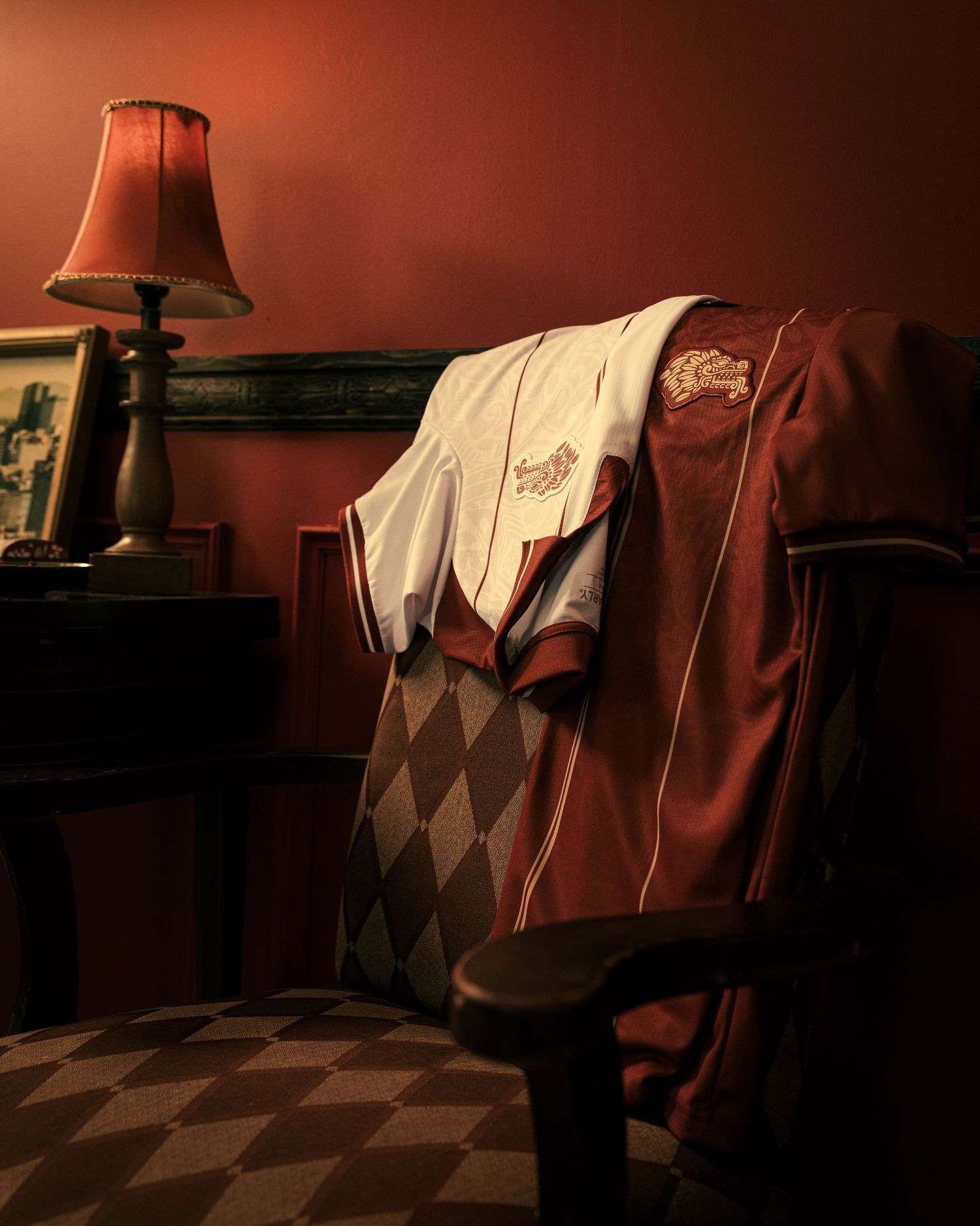 Moody interior scene with dark red walls and checkered floor pattern illuminated by soft lamp lighting.