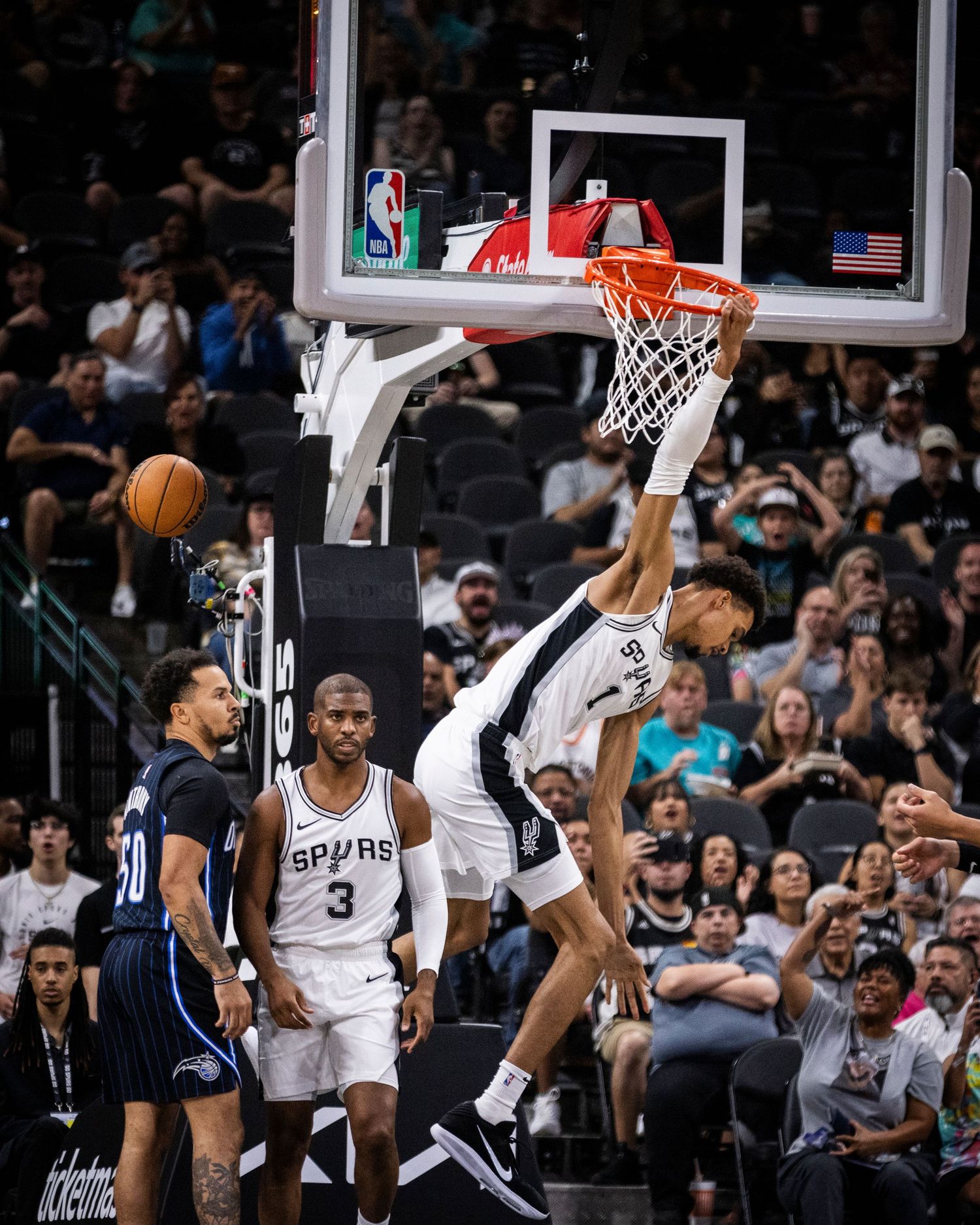 Basketball players battle for position under the hoop during an NBA game. Victor Wembanyama