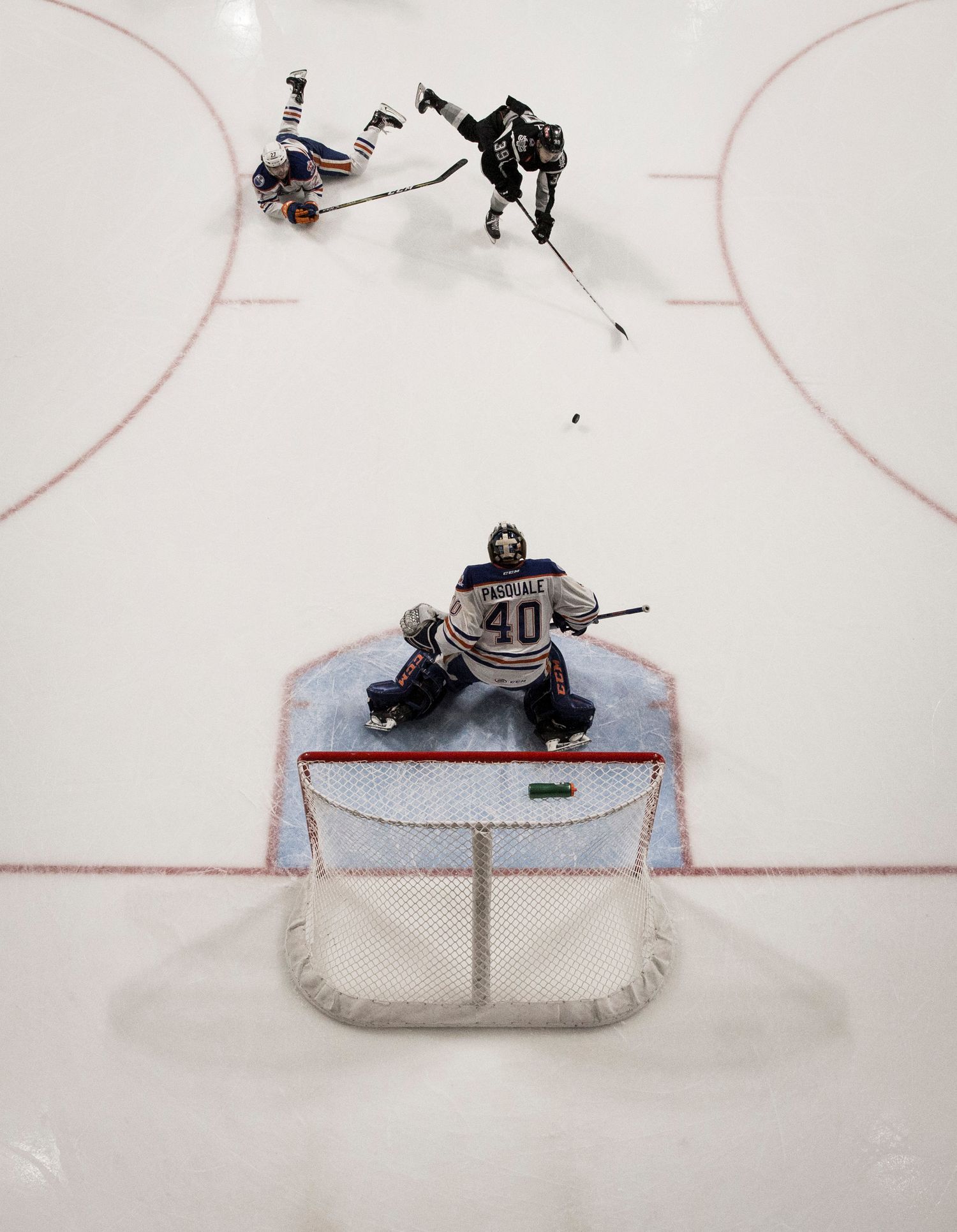 Aerial view of hockey players facing off against a goalie in net.