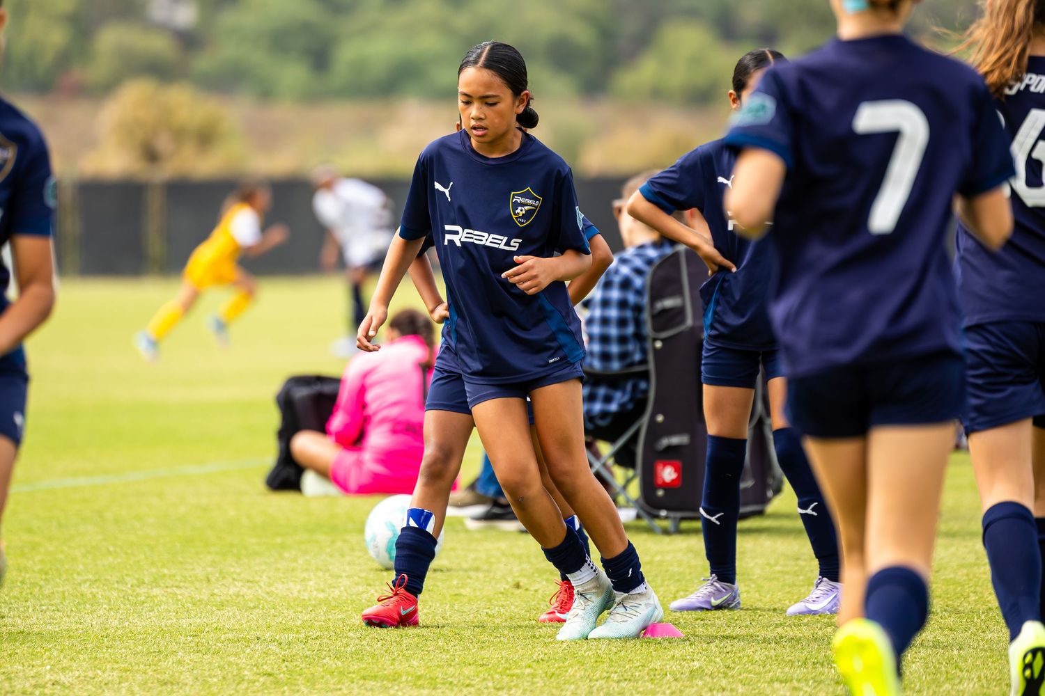 Soccer players in navy uniforms practice drills on grass field.