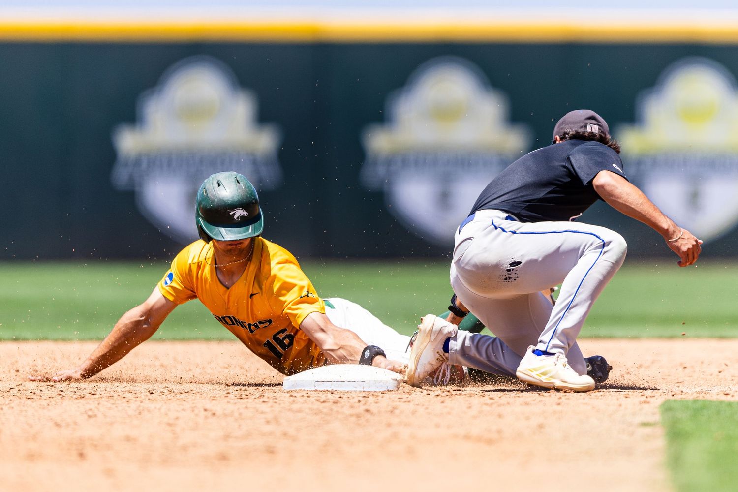 Baseball player in yellow uniform slides into second base as fielder in black uniform attempts the tag.