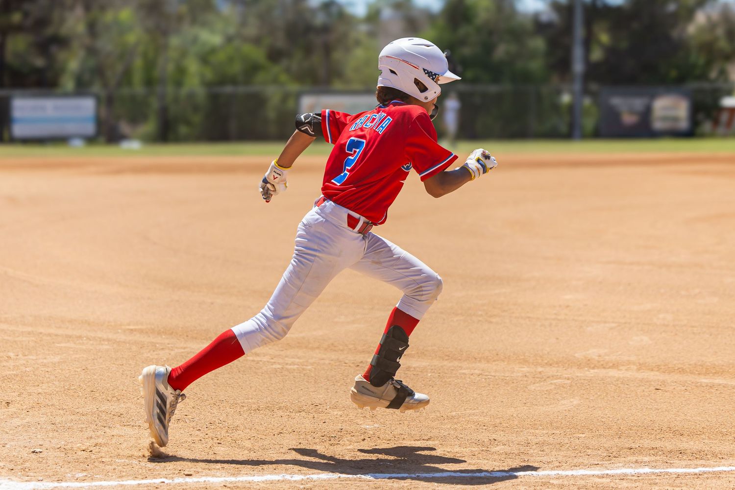 Baseball player in red and white uniform runs bases during game.