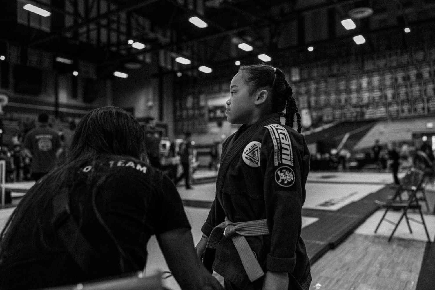 Martial arts competitors prepare for match in indoor gymnasium.