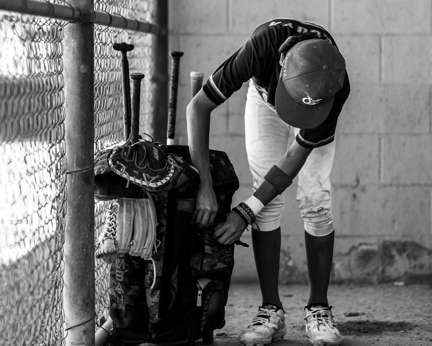 Baseball players preparing equipment in dugout before a game.