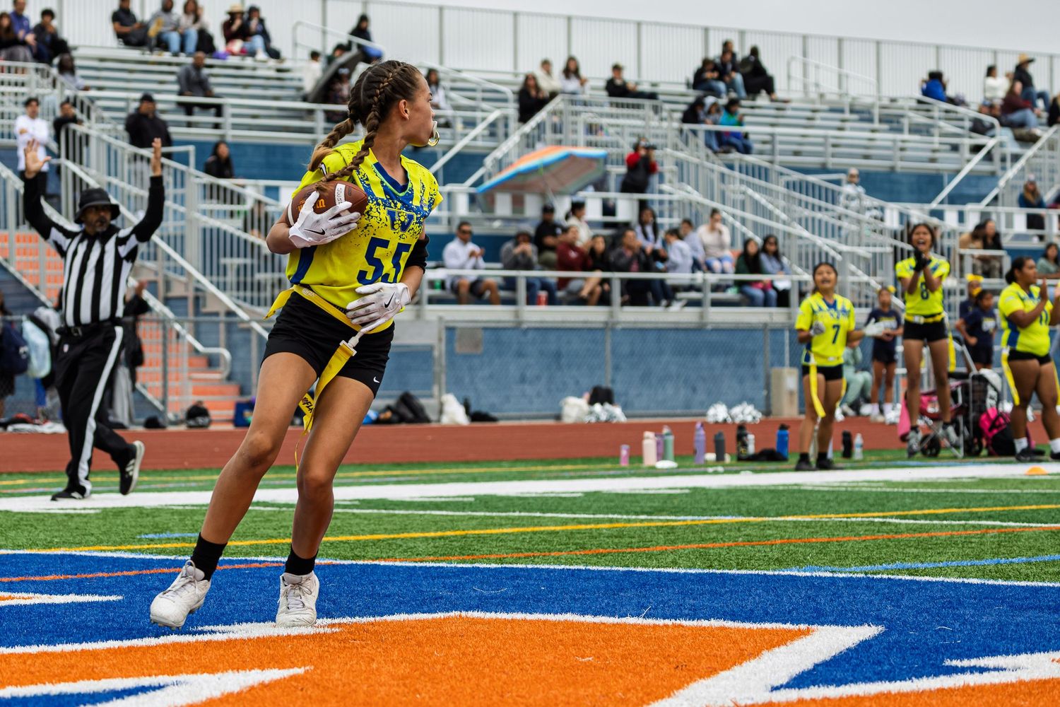 Girl's flag football athlete in yellow uniform scoring a touchdown.
