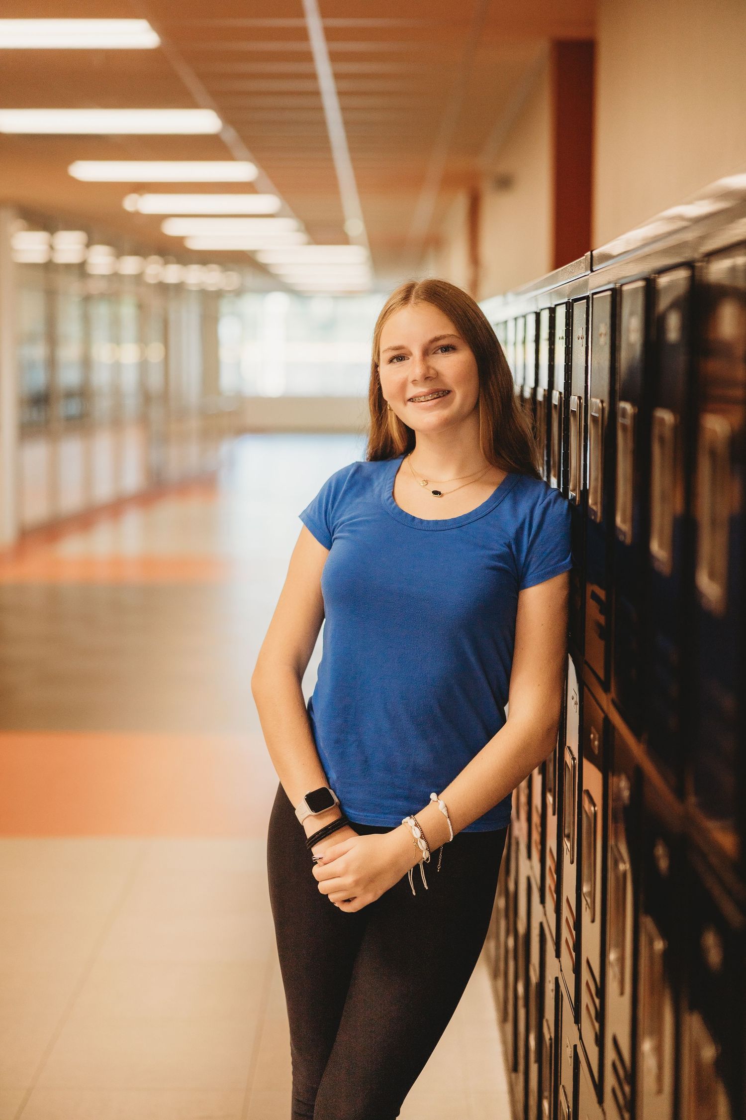 School hallway with lockers and fluorescent lighting featuring casual portrait poses.