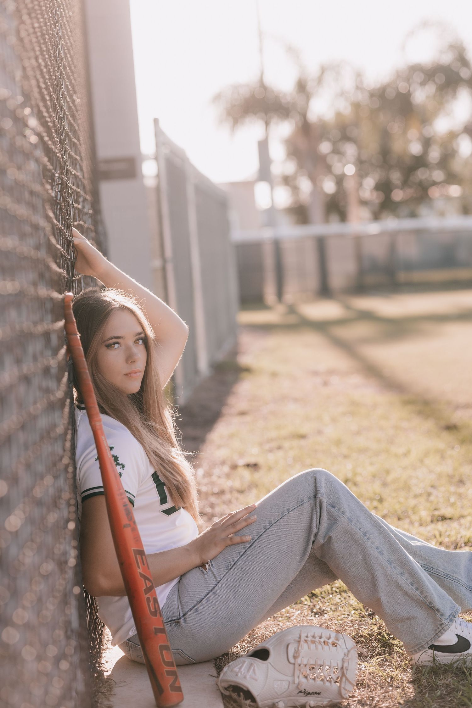 Relaxed outdoor portrait session against a rustic wall in natural lighting.