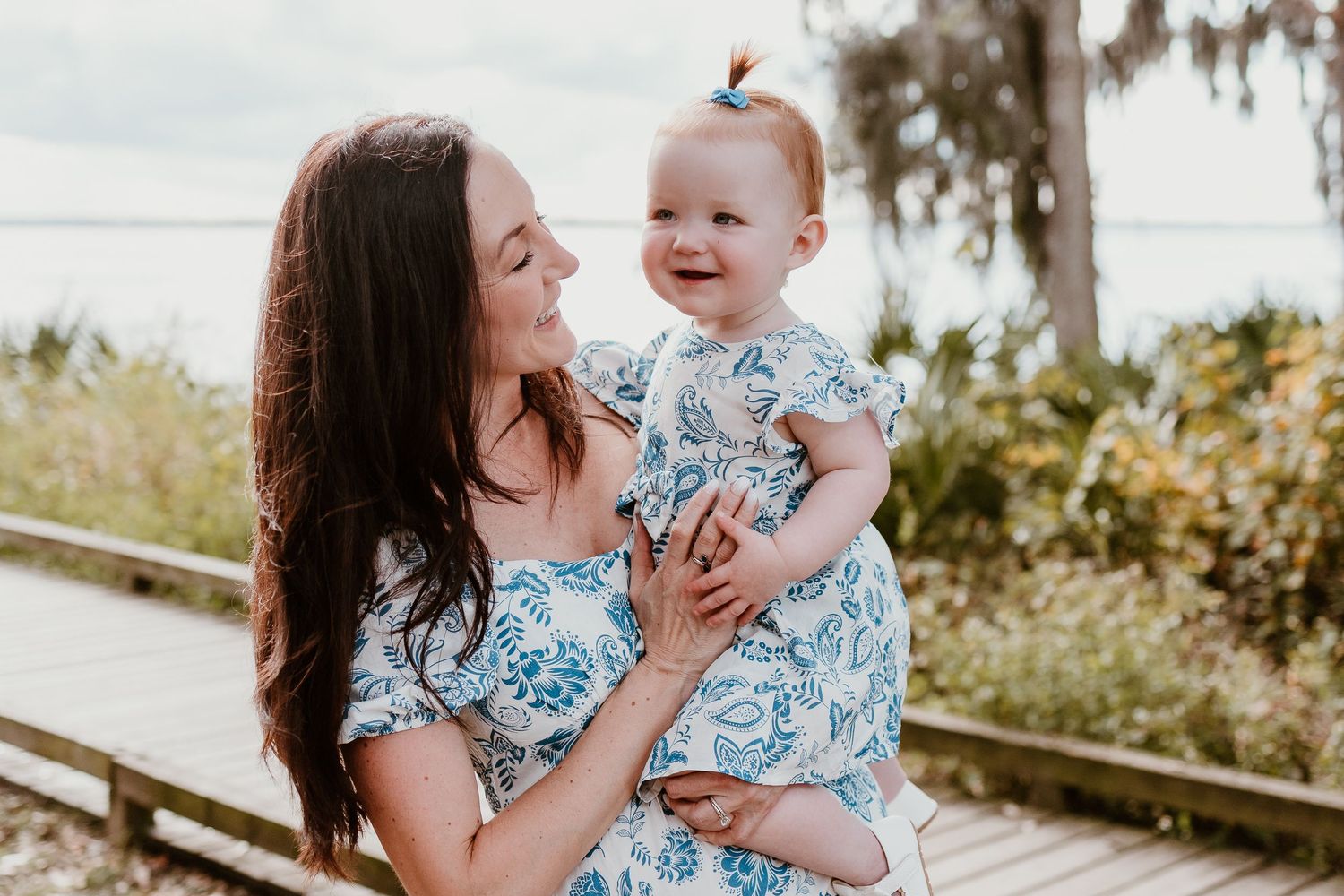 Parent and child in matching blue floral outfits share joyful moments together outdoors.