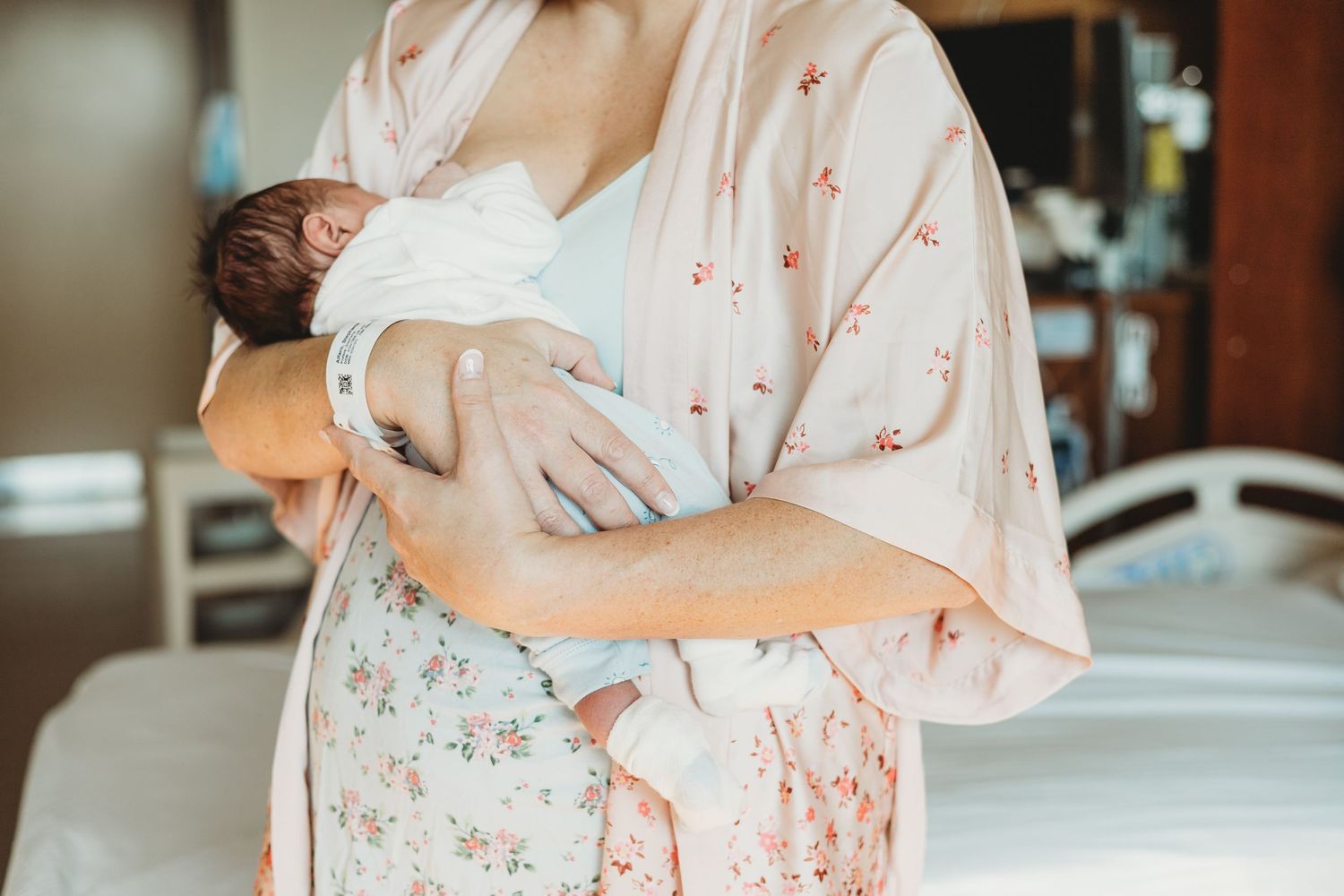 Parents cradling their newborn baby in a floral patterned outfit.