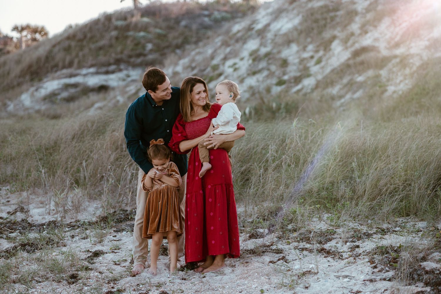A family portrait session at sunset on a sandy hill with warm evening light.