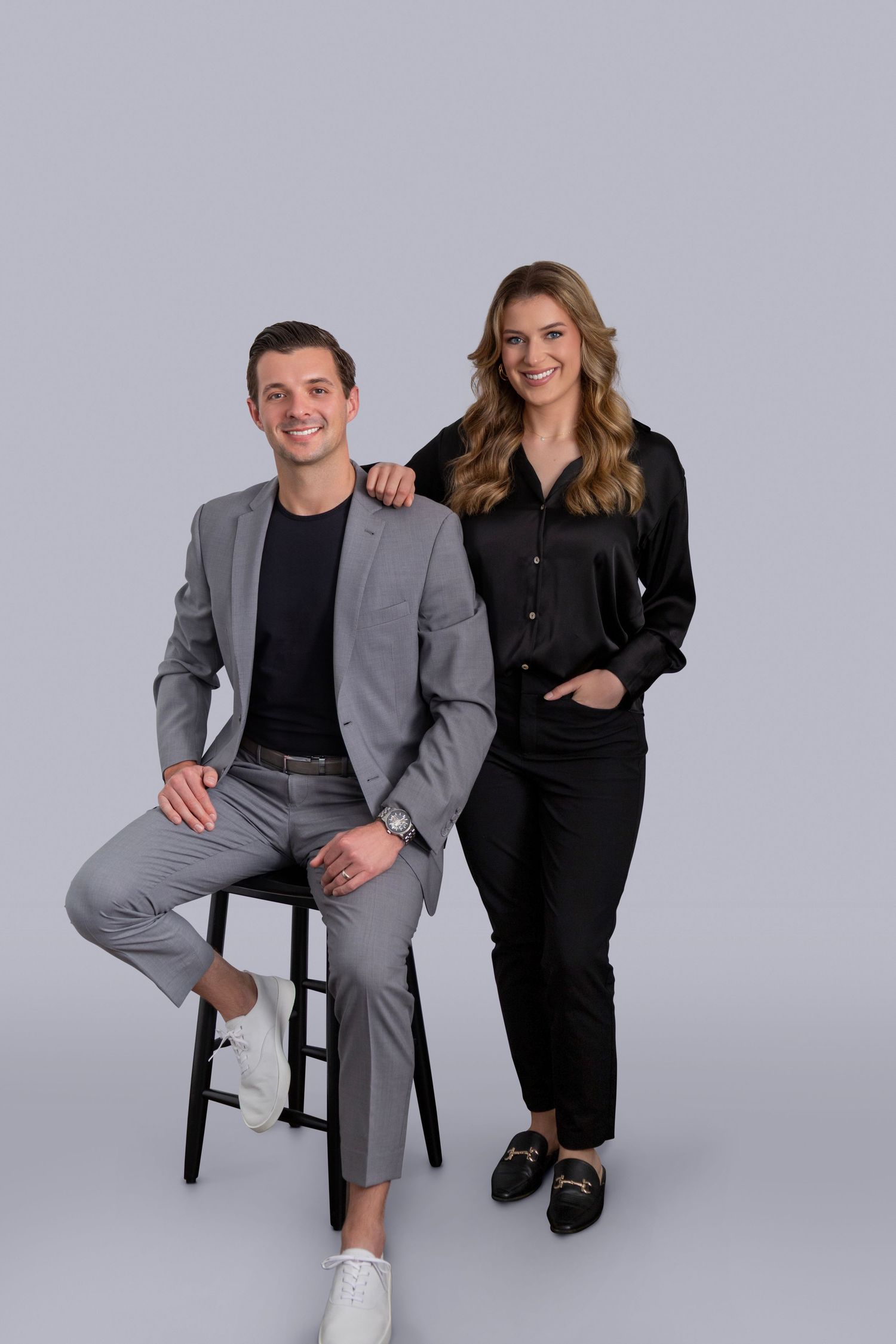 Business portrait series with people in grey suit and black outfit against light background.