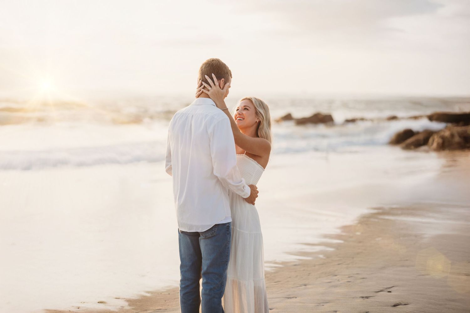 Romantic beach engagement photos captured during golden hour with ocean waves in background.