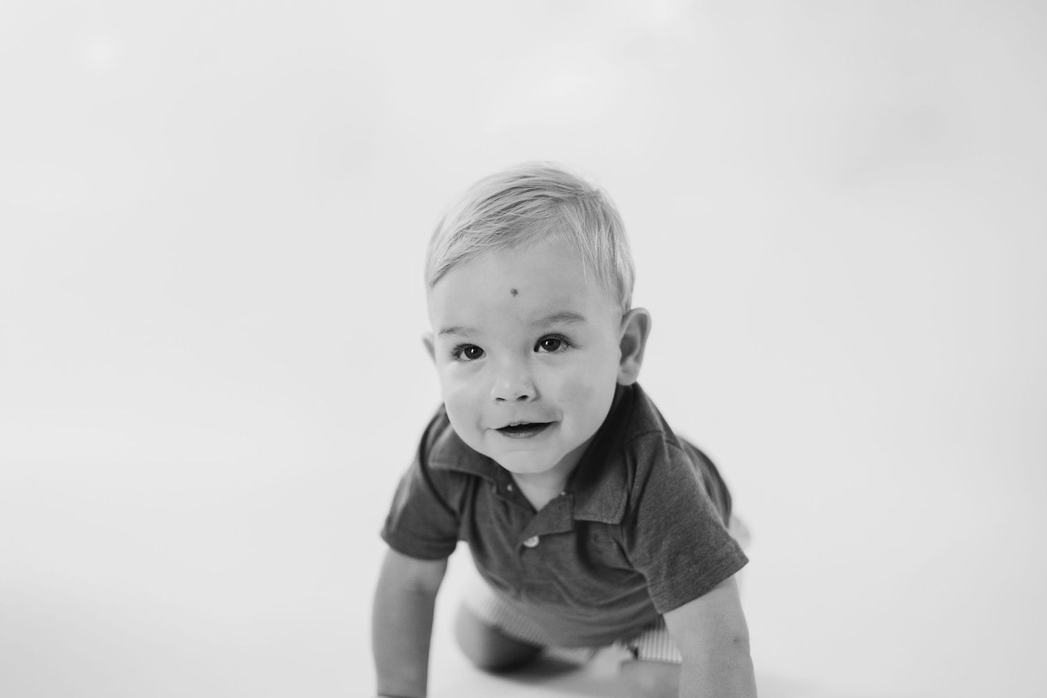 Black and white photo series showing a baby crawling and playing in different poses on a white background.