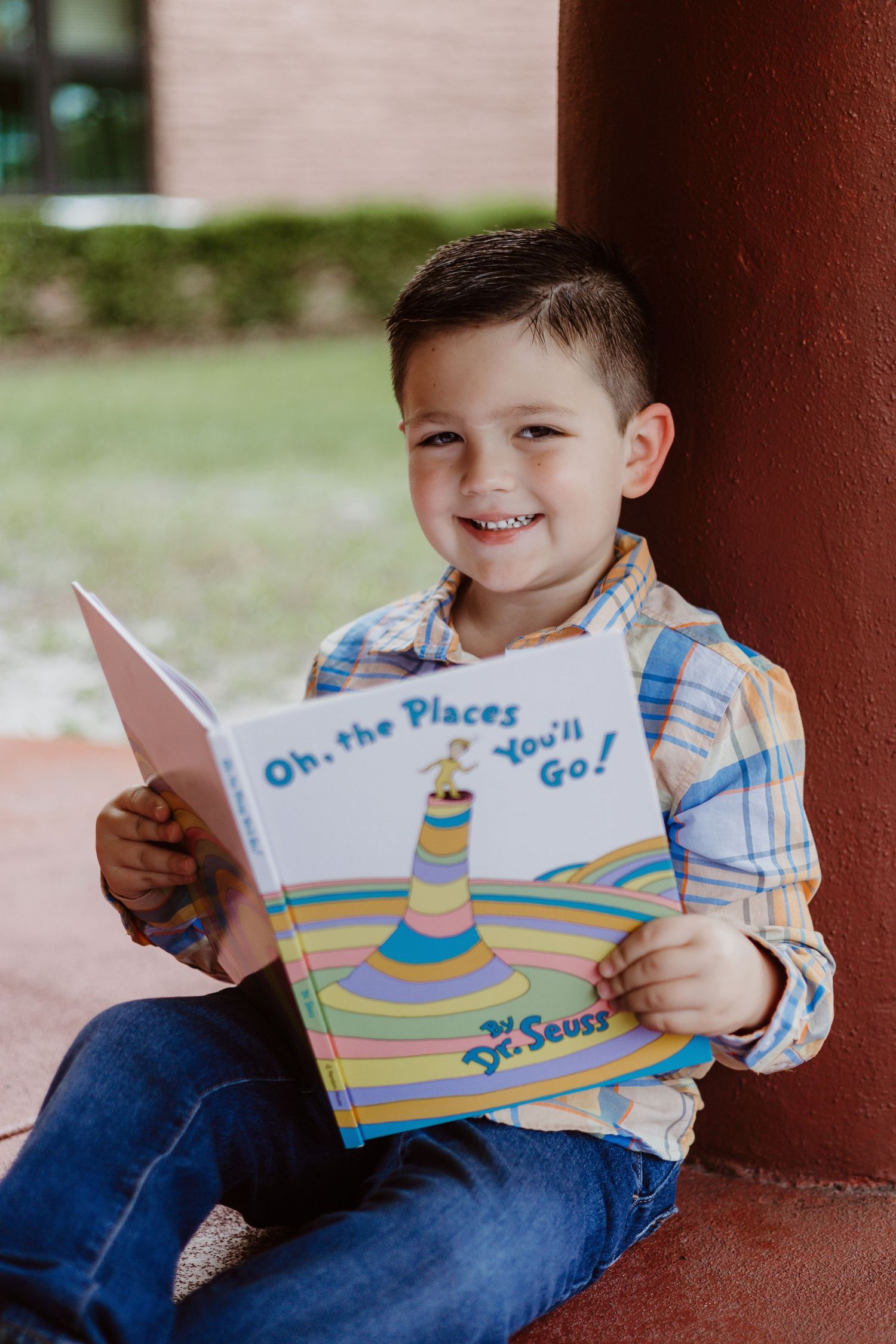 A series of photos showing a child reading Dr. Seuss's 'Oh, The Places You'll Go!' book while sitting outdoors.