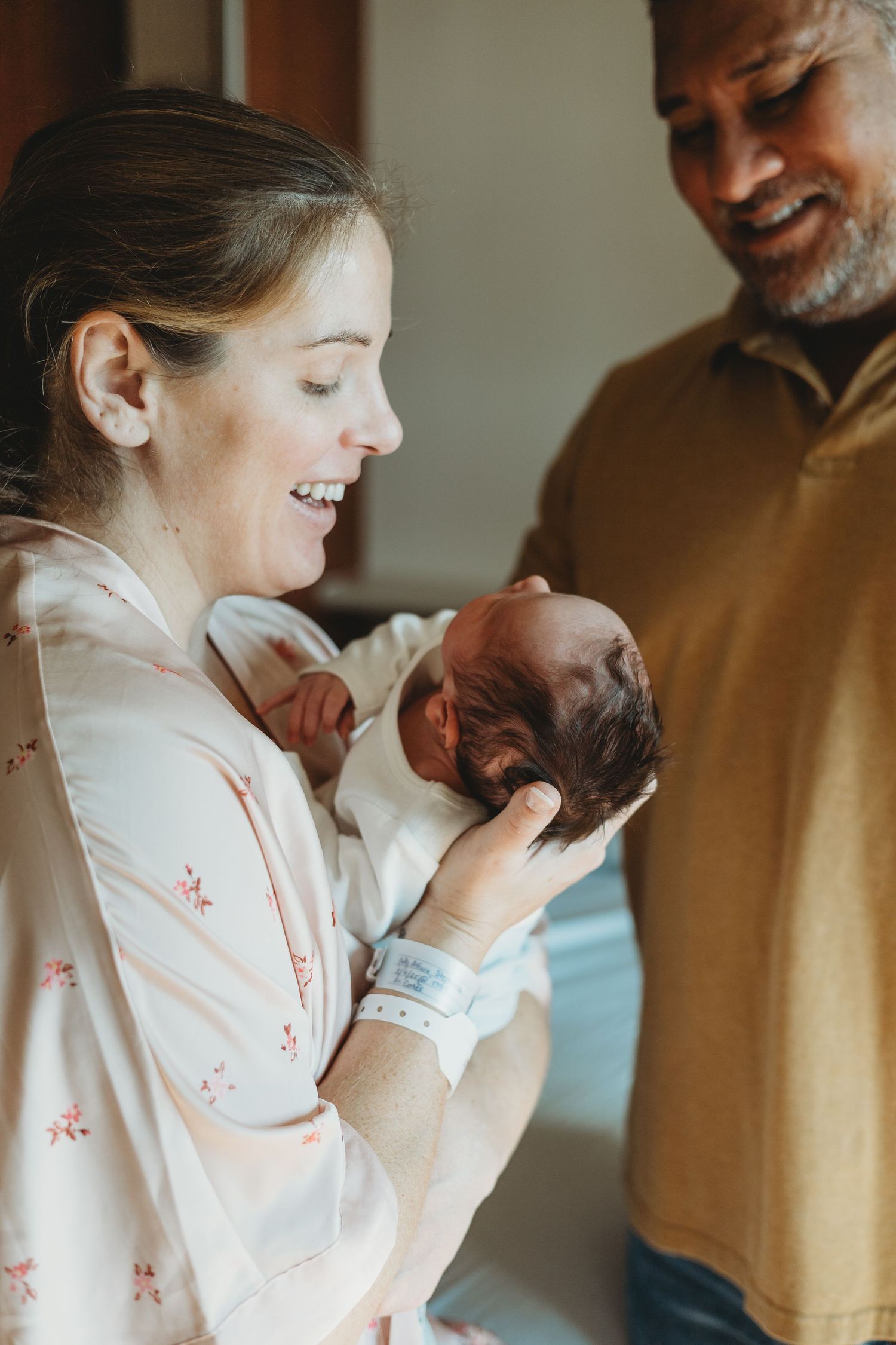 Tender moment between parents and their newborn baby in warm lighting.