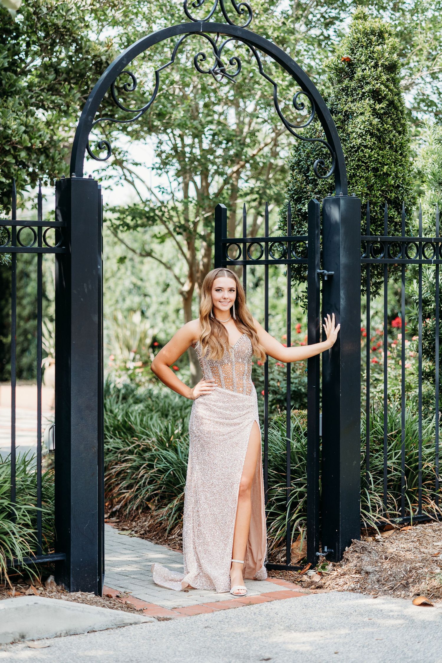 Decorative black iron gate entrance surrounded by lush landscaping and greenery.