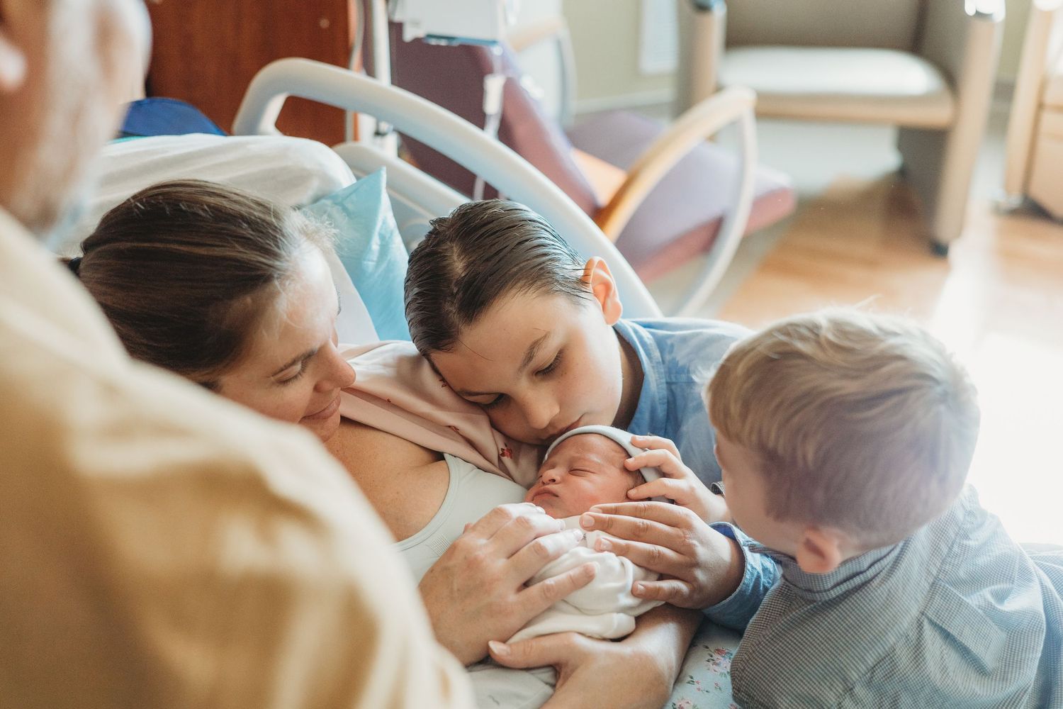 Family members gathered around to look at a newborn baby.