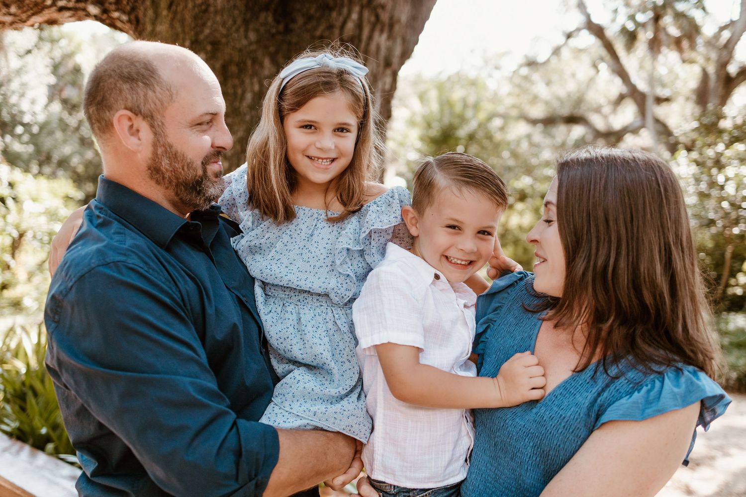 A loving family shares joyful moments together during an outdoor photo session in a natural setting.