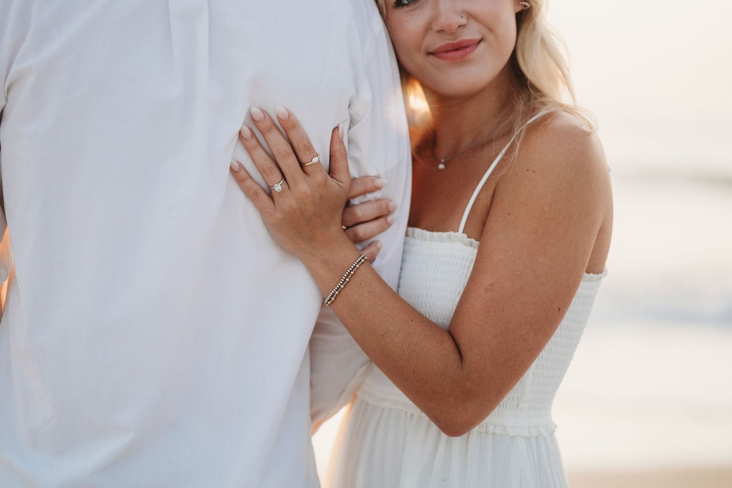 A couple shares an intimate moment on the beach during golden hour.