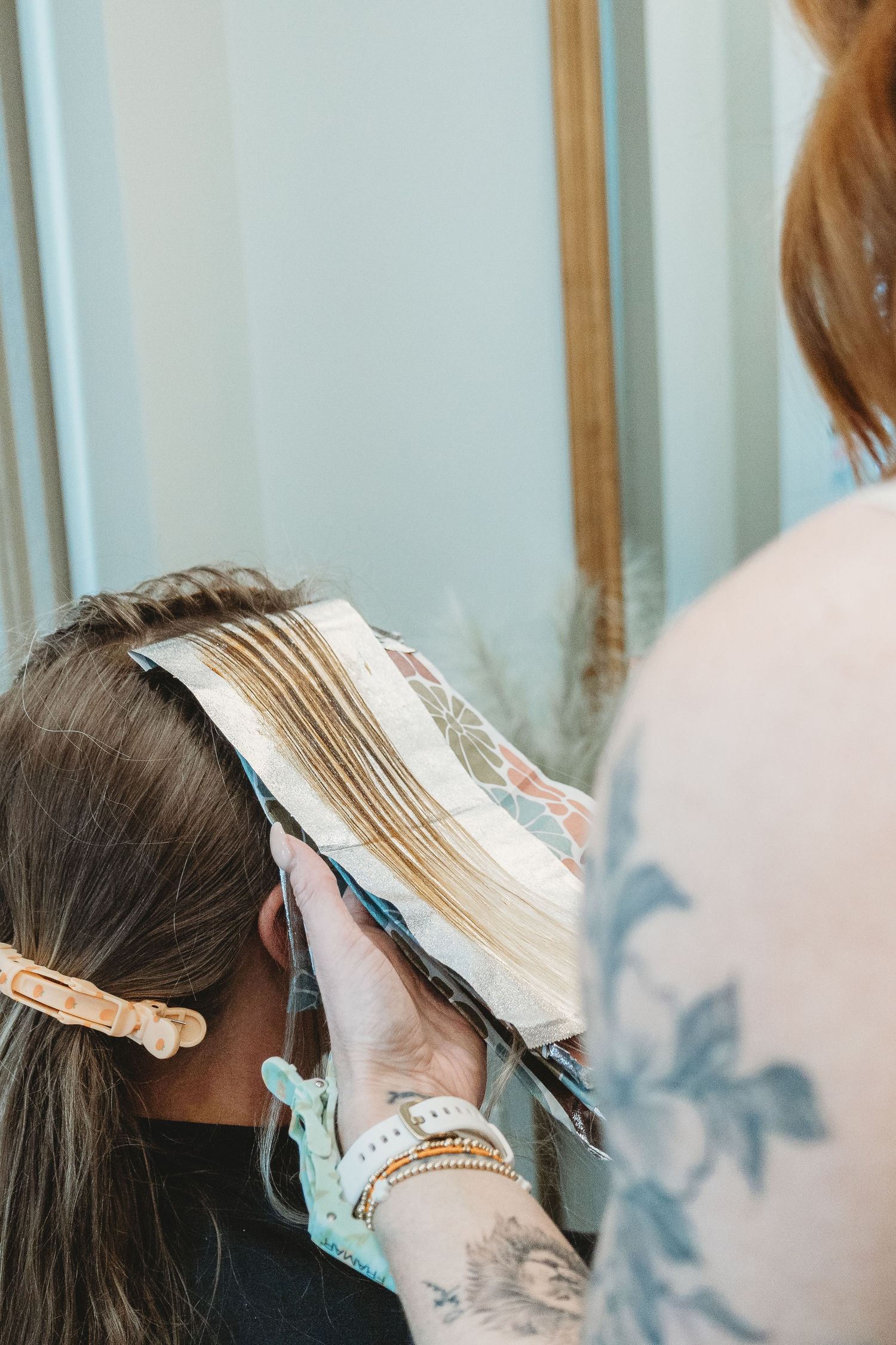 Hair coloring process showing foils being applied during a salon treatment.
