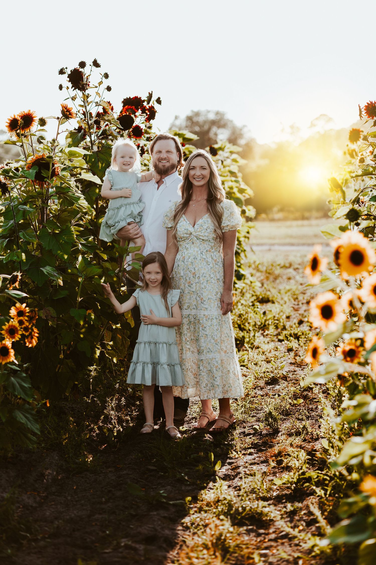 Candid family moment captured in sunflower field during golden hour.
