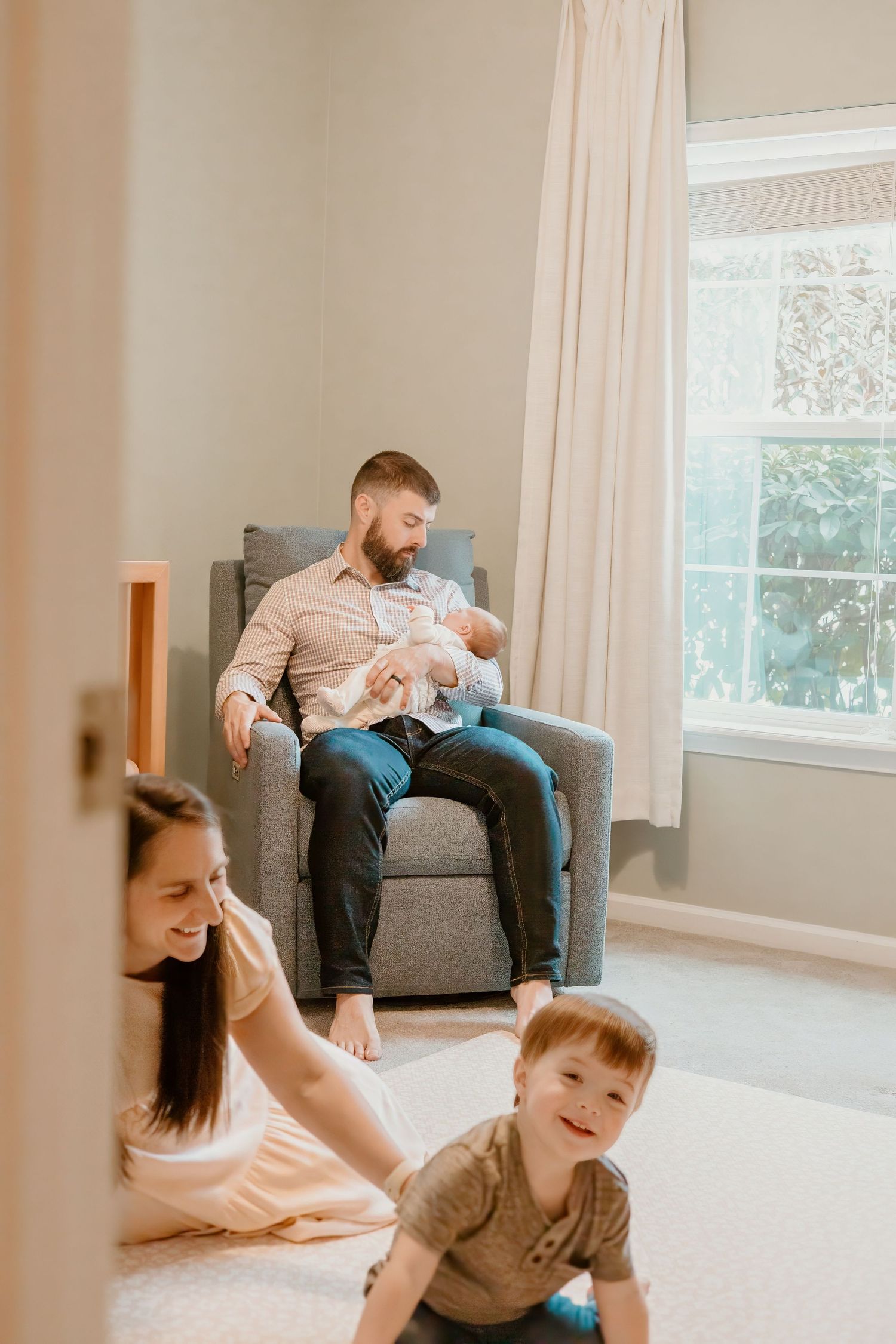Family playing and laughing together in bright living room with grey furniture.