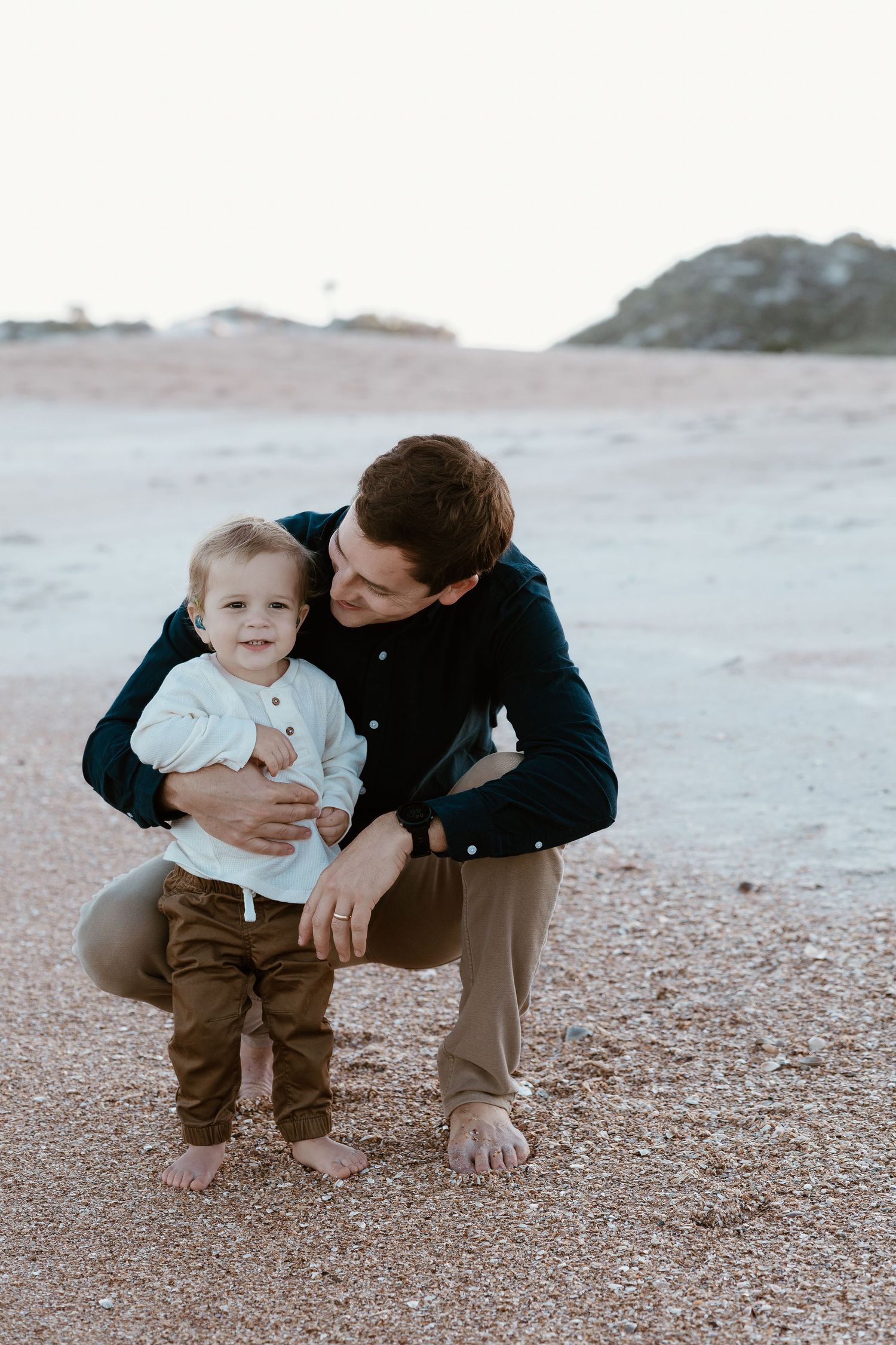 A tender moment captured on a rocky beach during a casual family photoshoot.