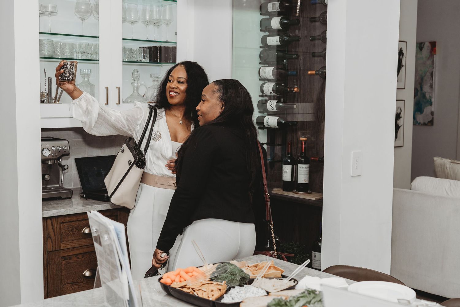 Group celebrating in modern kitchen with white cabinets and marble countertops.