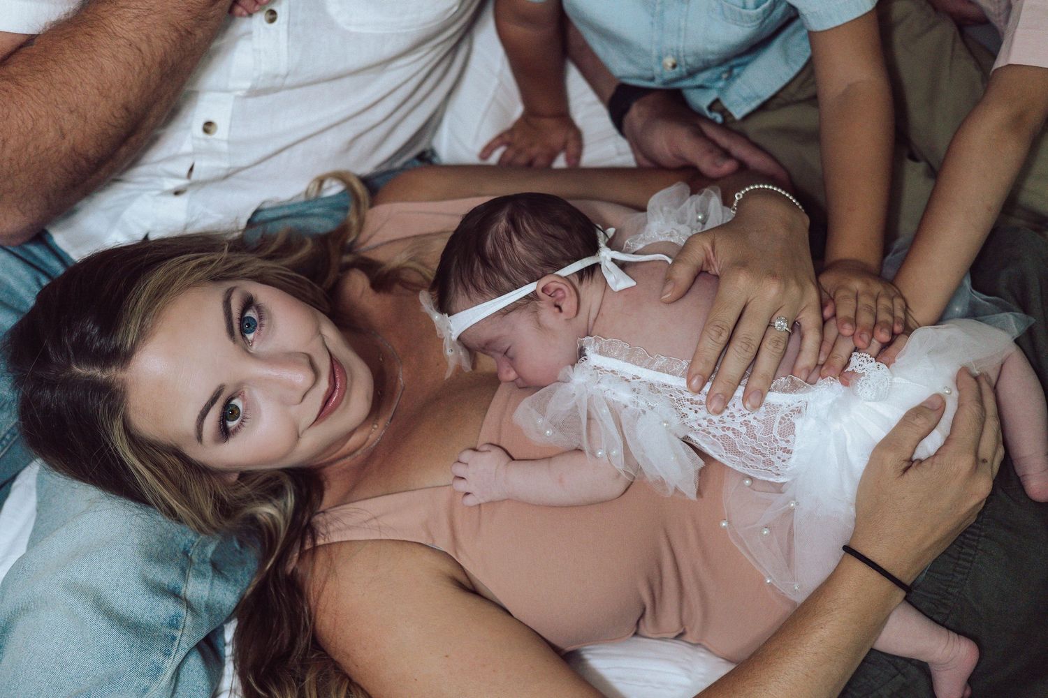 Family members cuddling together on bed during intimate photo session.