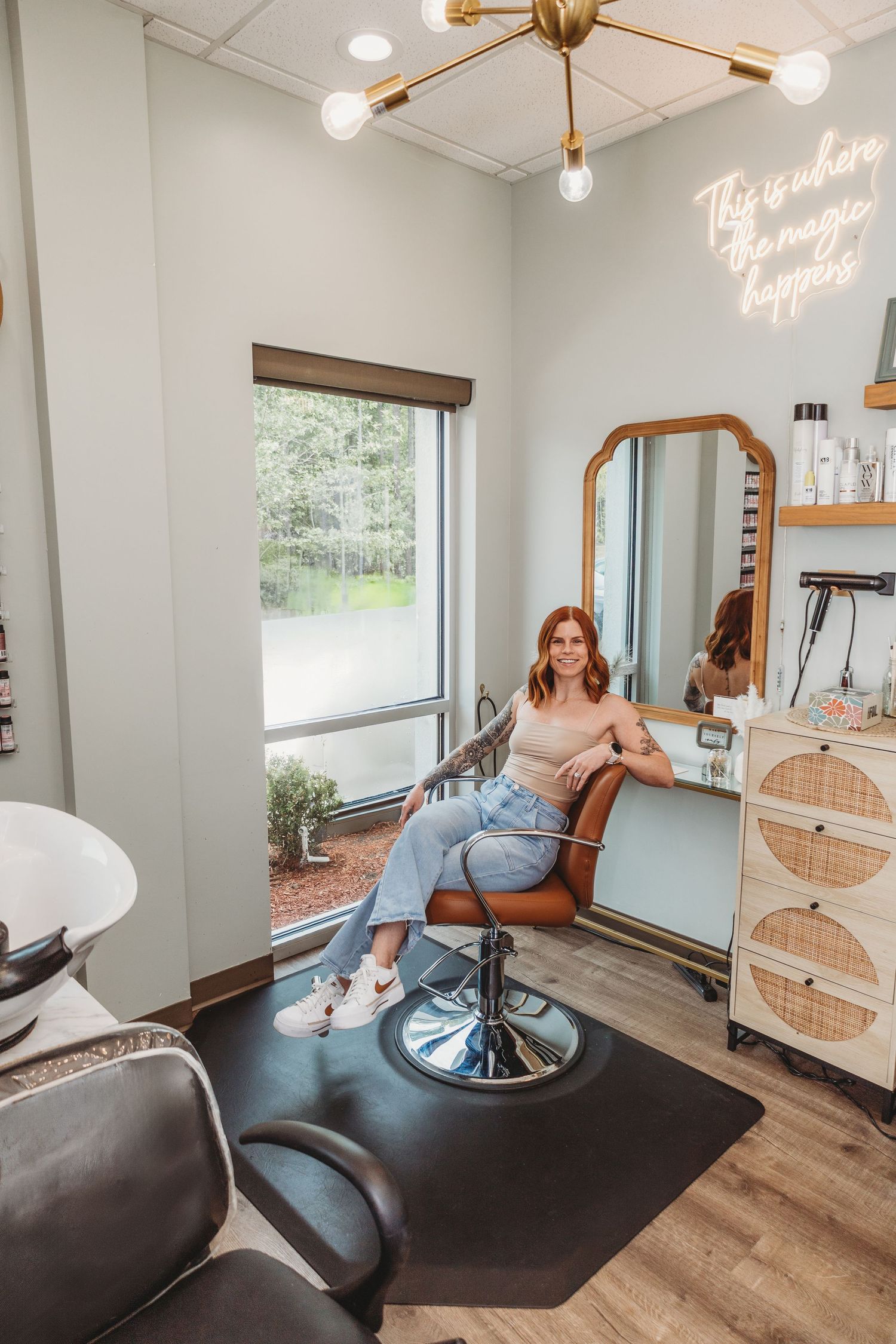 Modern hair salon interior with gold lighting fixtures, wooden floors, and minimalist decor.