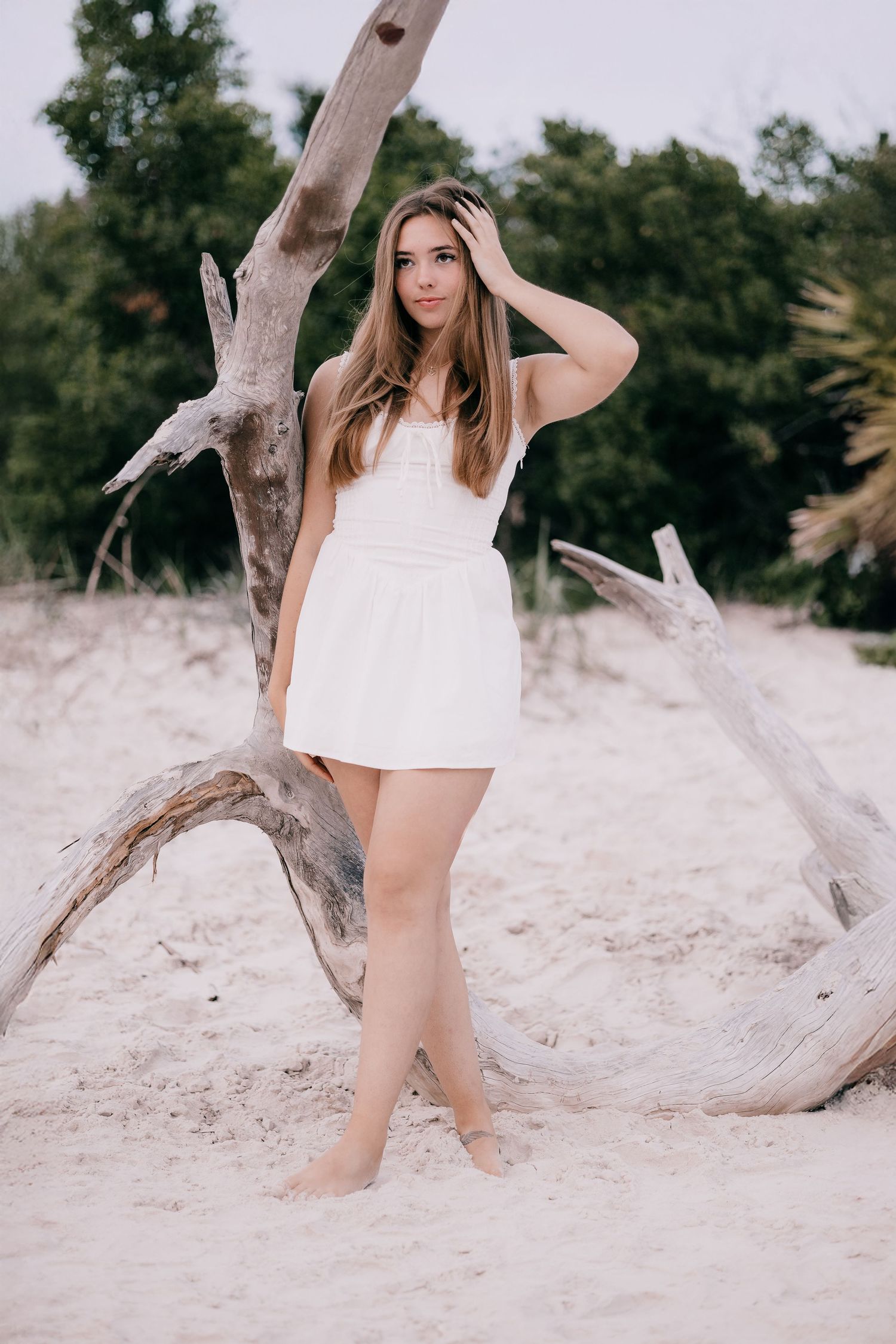 Casual beach portraits with weathered driftwood on white sand.
