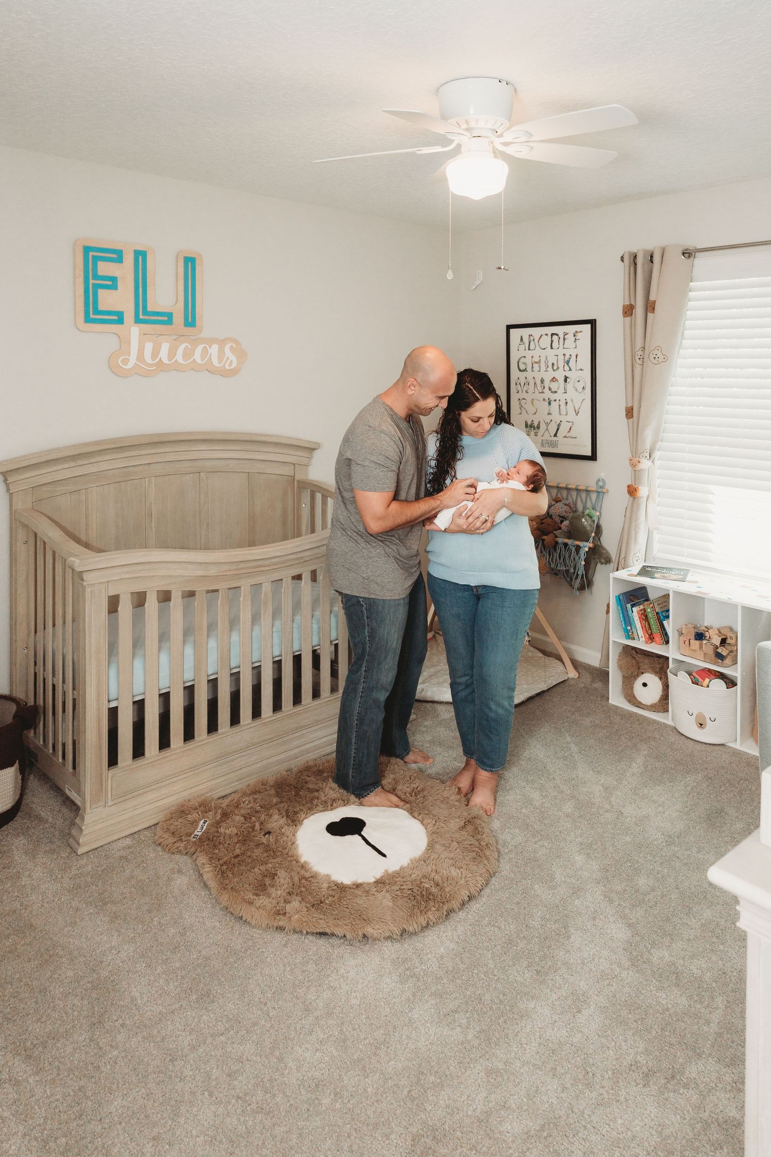 Modern nursery room with gray crib, turquoise name decor, and plush rug.