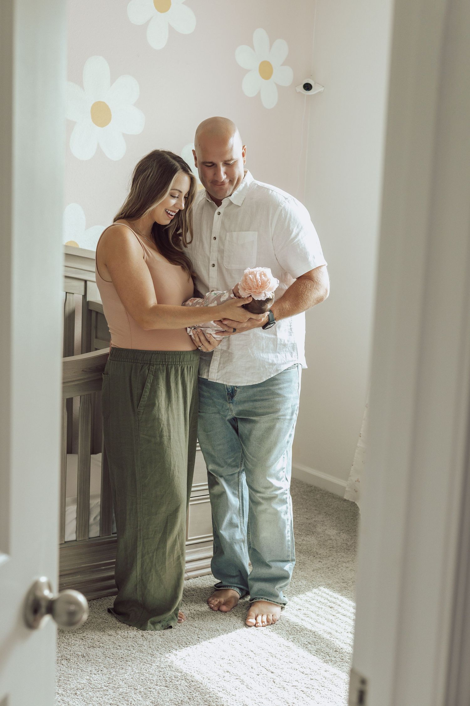Intimate family moment captured in a bright nursery with floral wall decals.
