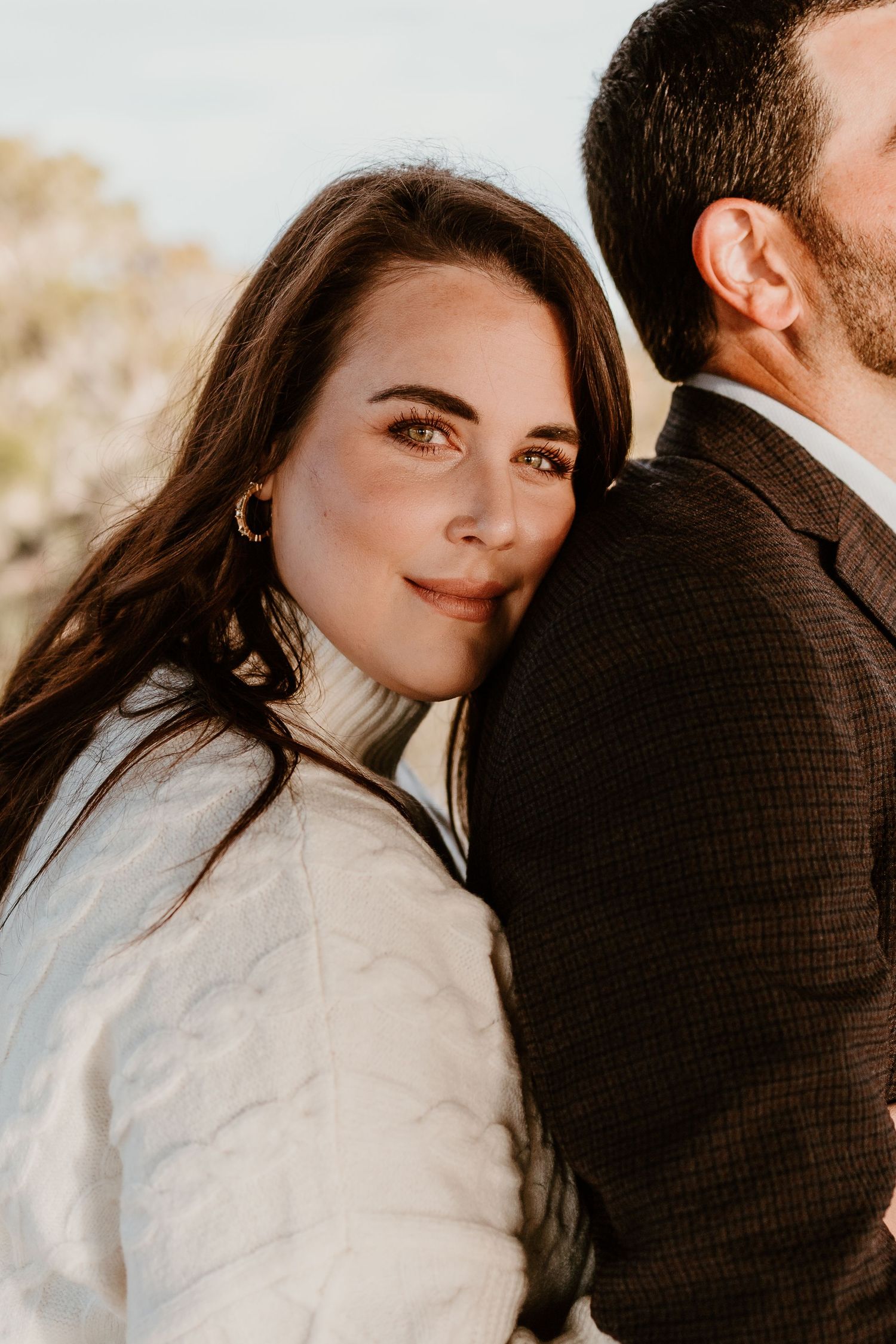 Close up portrait of couple in white and brown jackets during golden hour outdoor photoshoot.