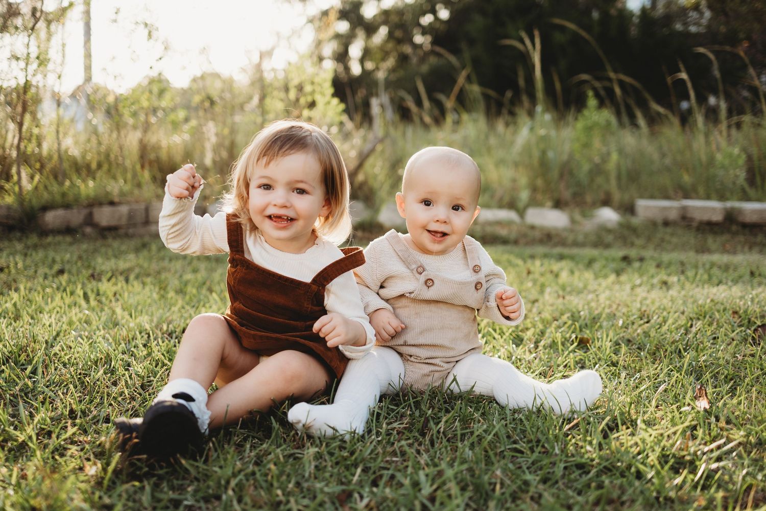Children sitting and playing together on green grass during a sunny summer day.