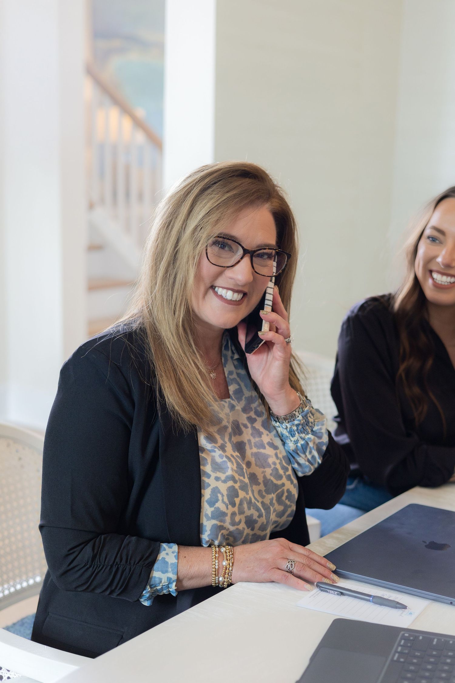 Business professional taking a phone call while sitting at desk with laptop.