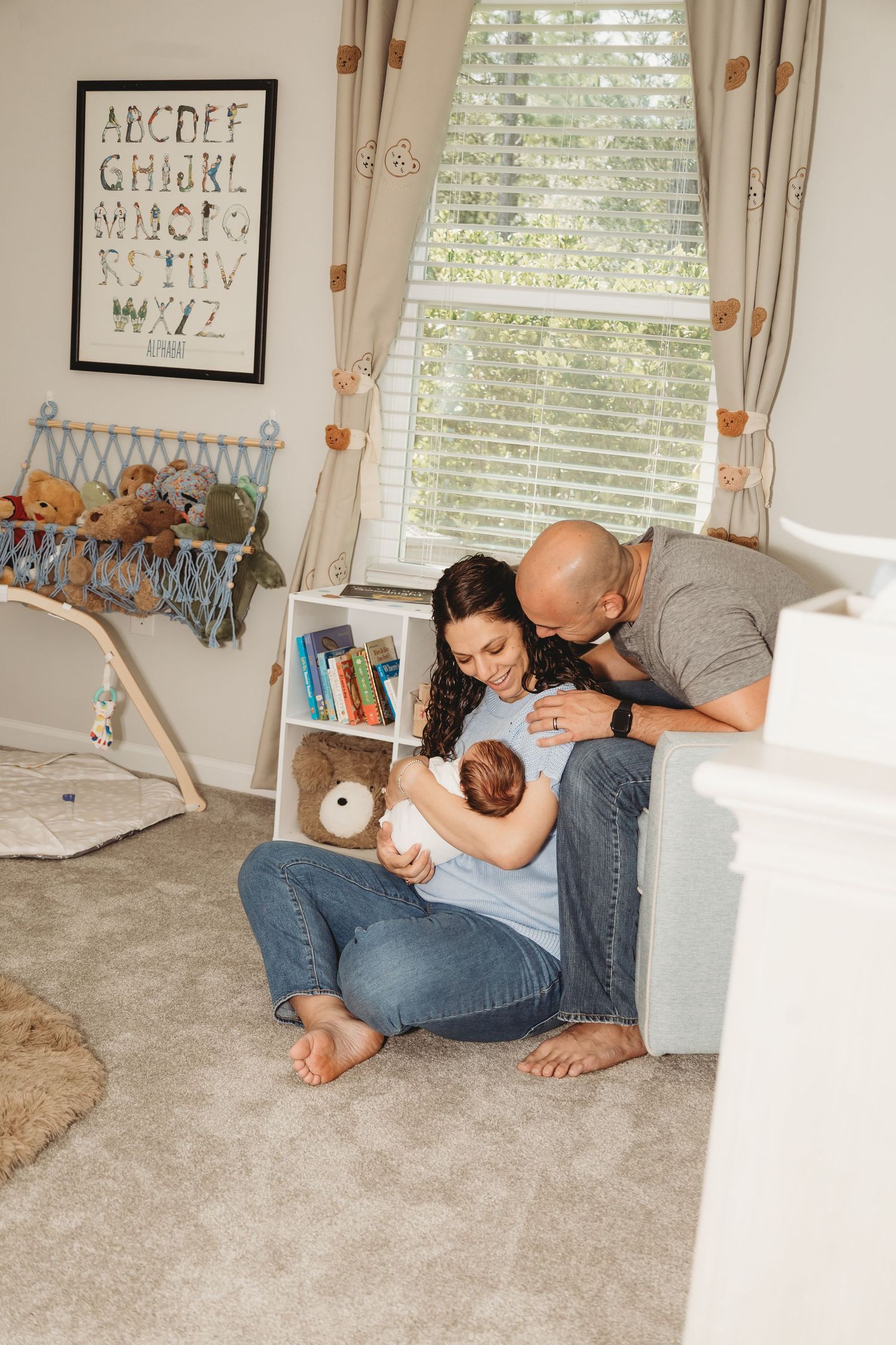 Cozy nursery room with alphabet wall art and stuffed animals near window.