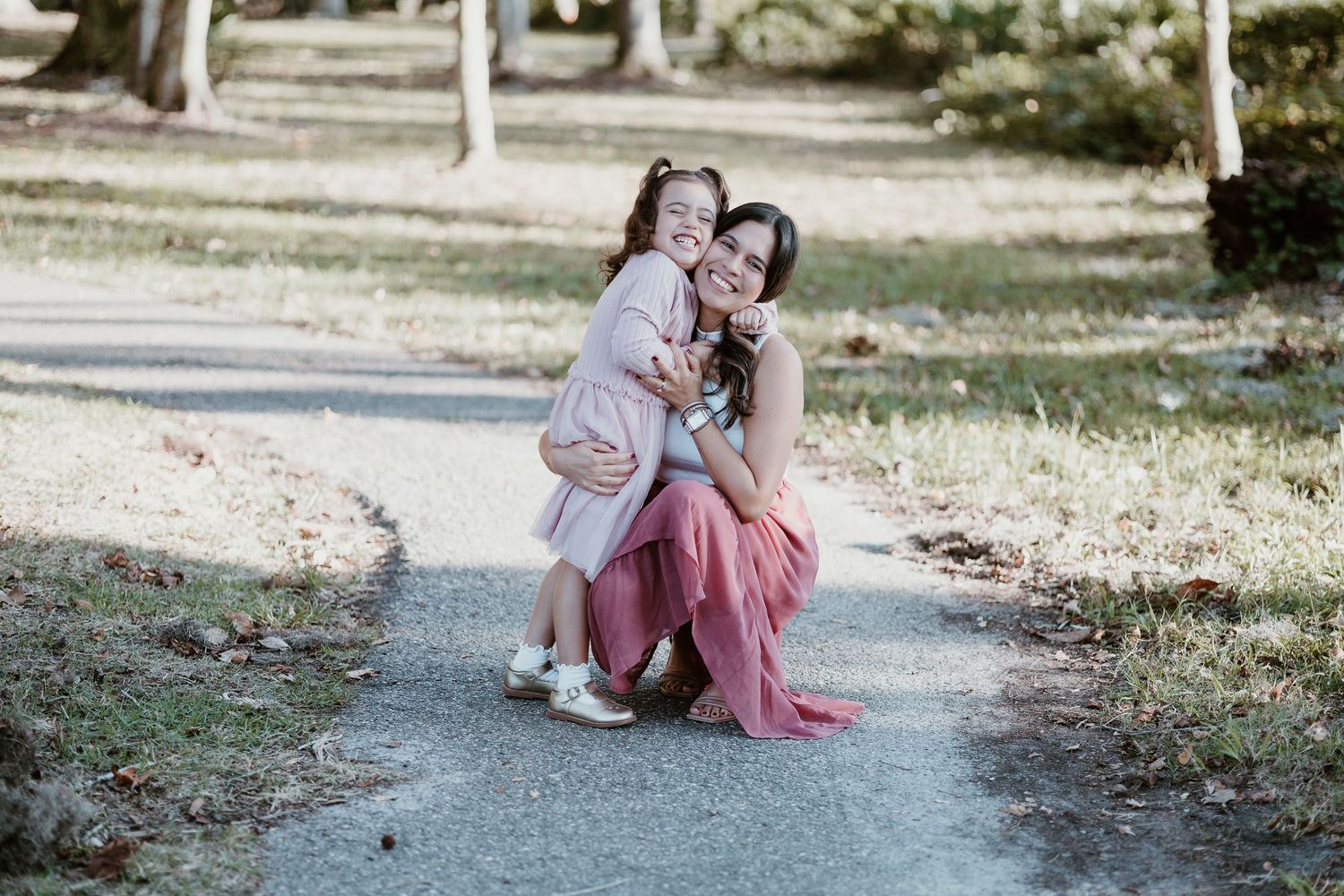 A sweet family interaction photographed on a winding park path in natural lighting.