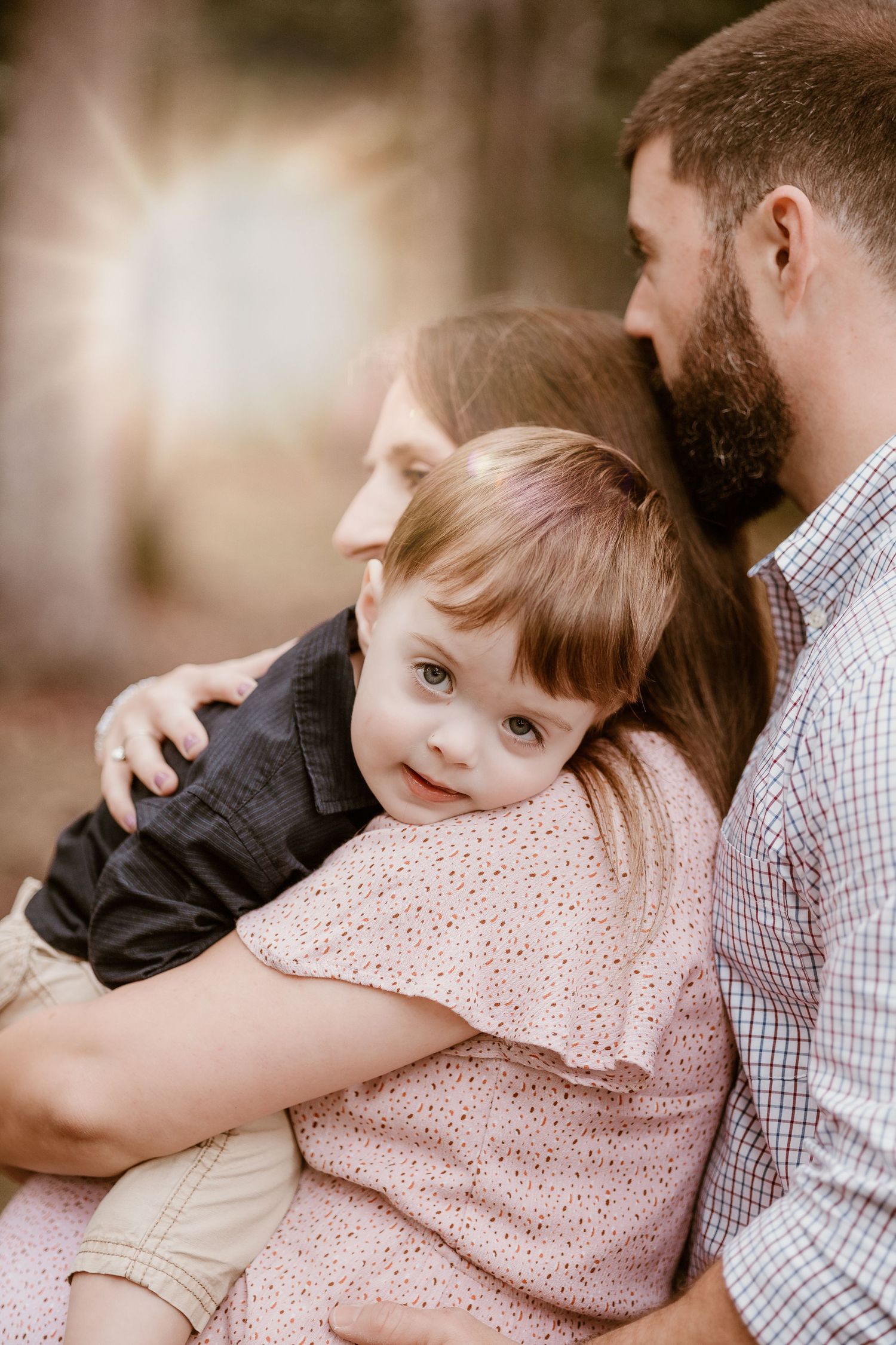 Sweet family moment captured in soft lighting with plaid shirt and floral dress.