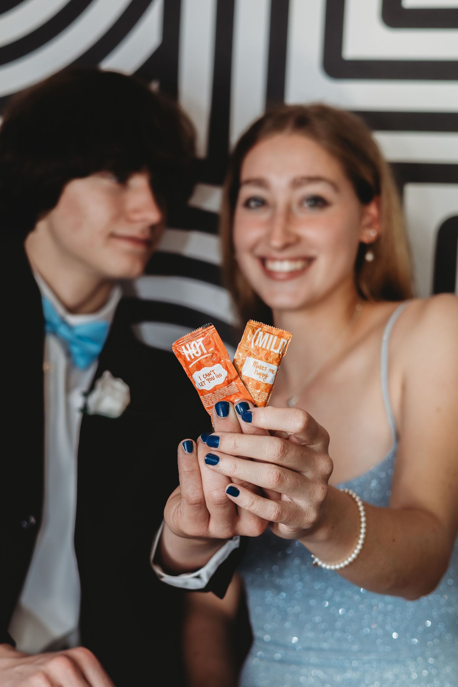 Holding up Taco Bell sauce packets with blue nail polish and formal attire.