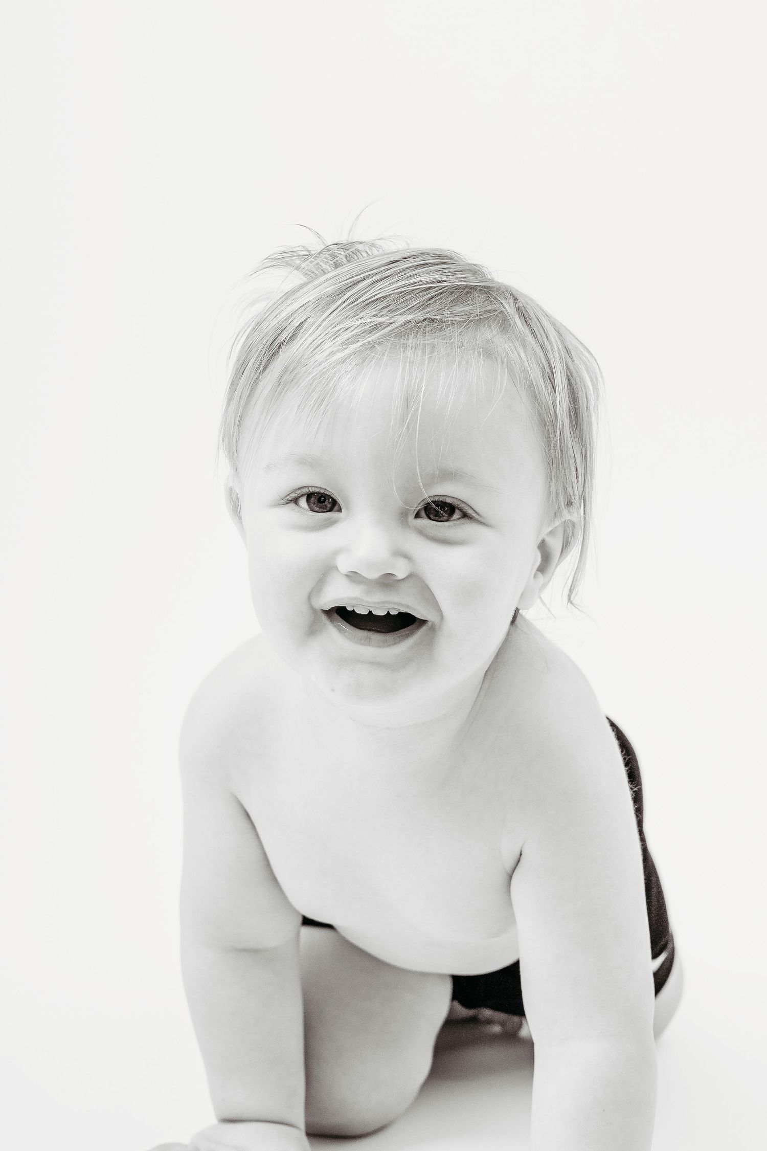 Black and white portrait of baby crawling on white background.