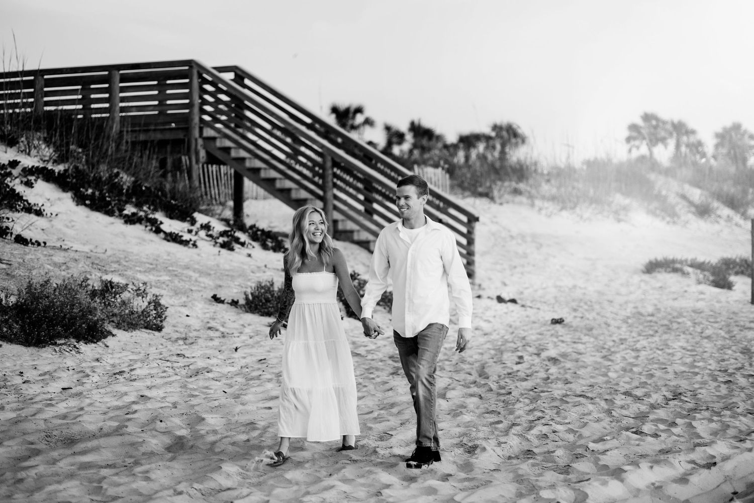 A romantic beach photoshoot featuring a couple walking along the sandy shore at sunset.