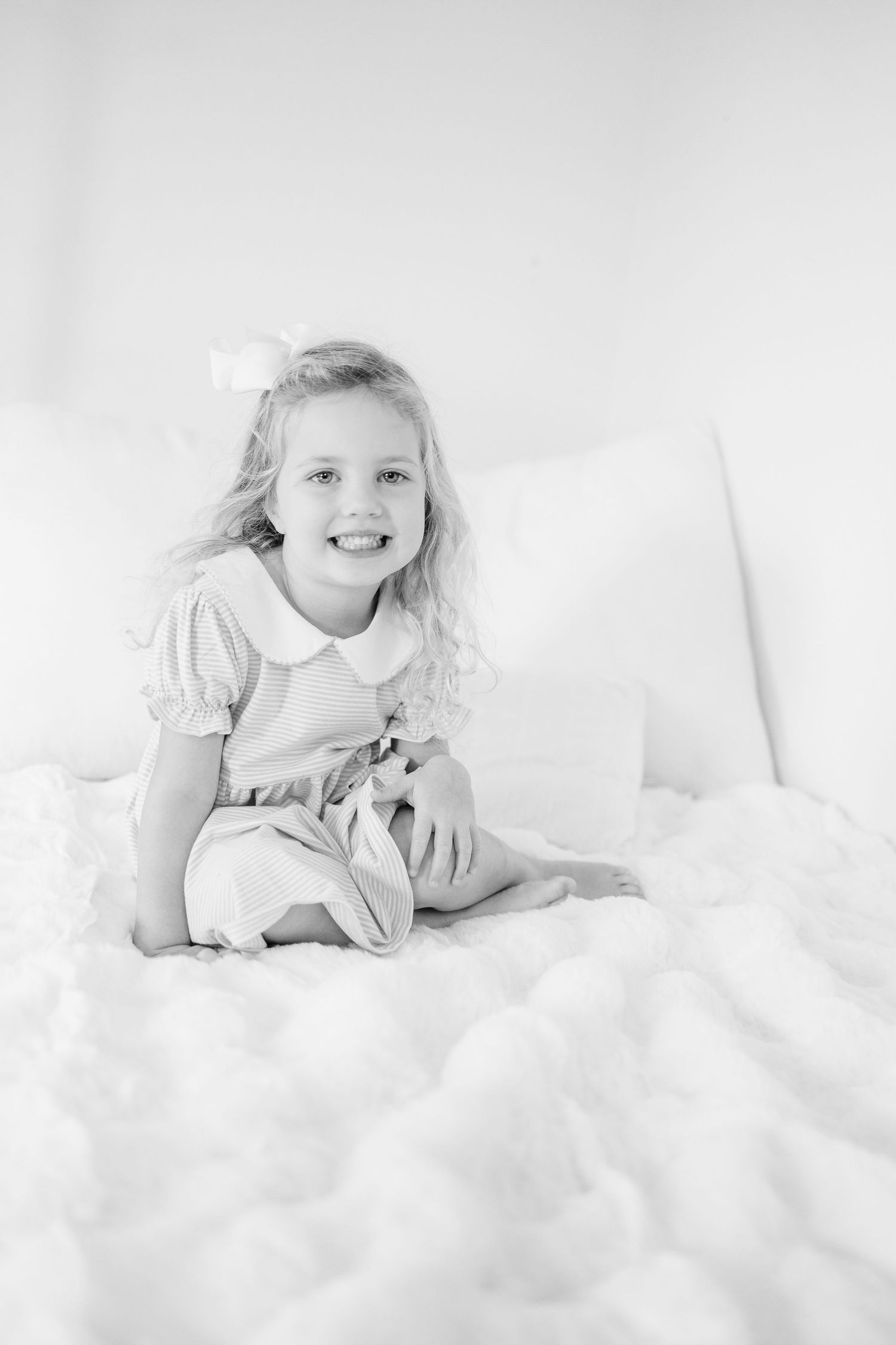 A series of high-key black and white portraits showing joyful expressions while lying on white bedding.