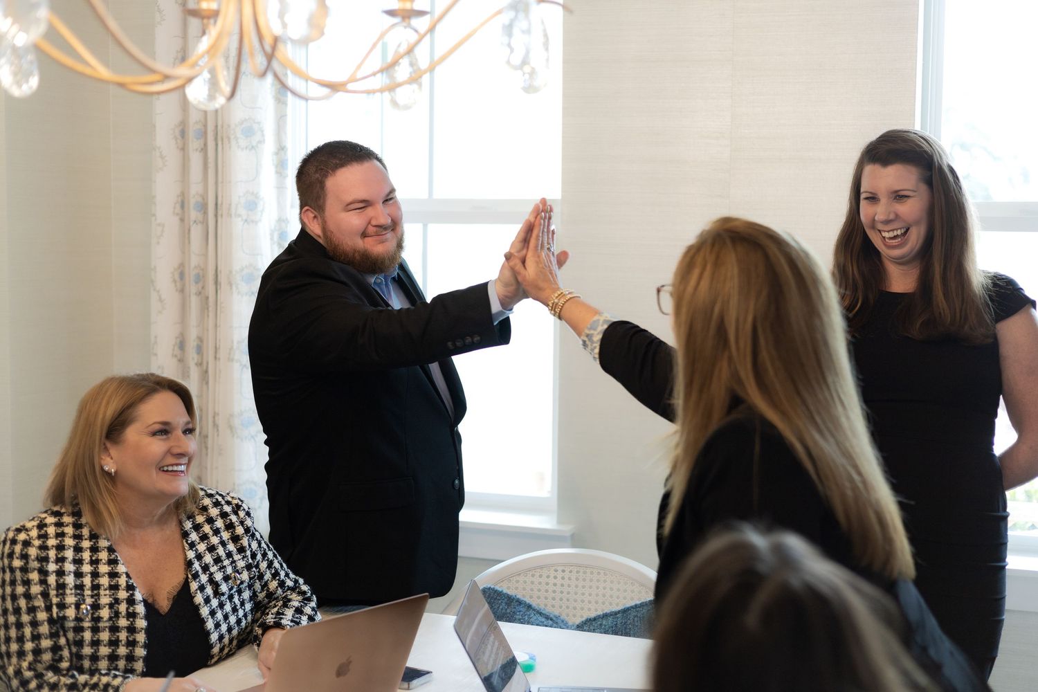 Colleagues celebrating with a high five during office meeting.