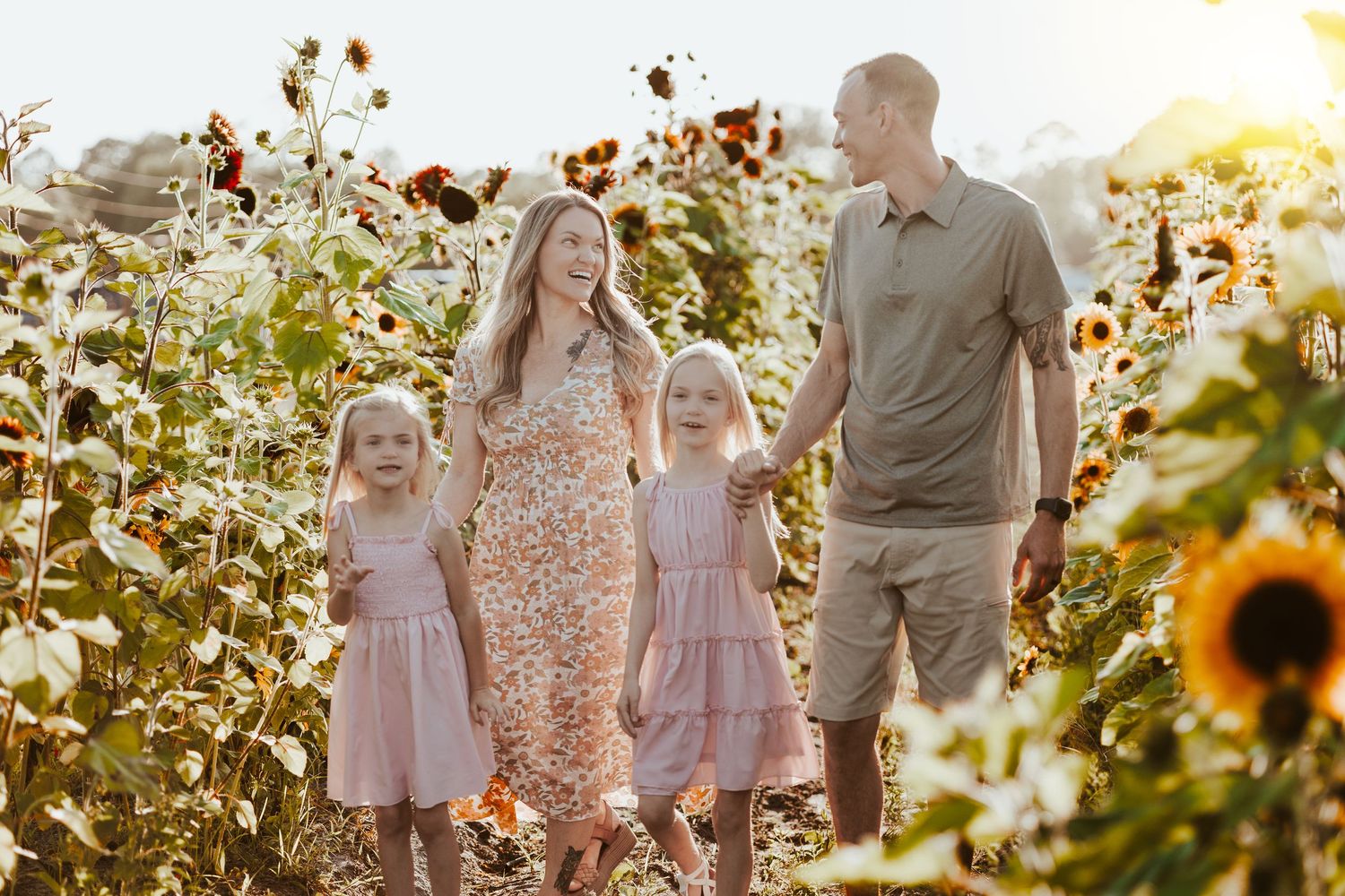 A family walks through a vibrant sunflower field during golden hour.