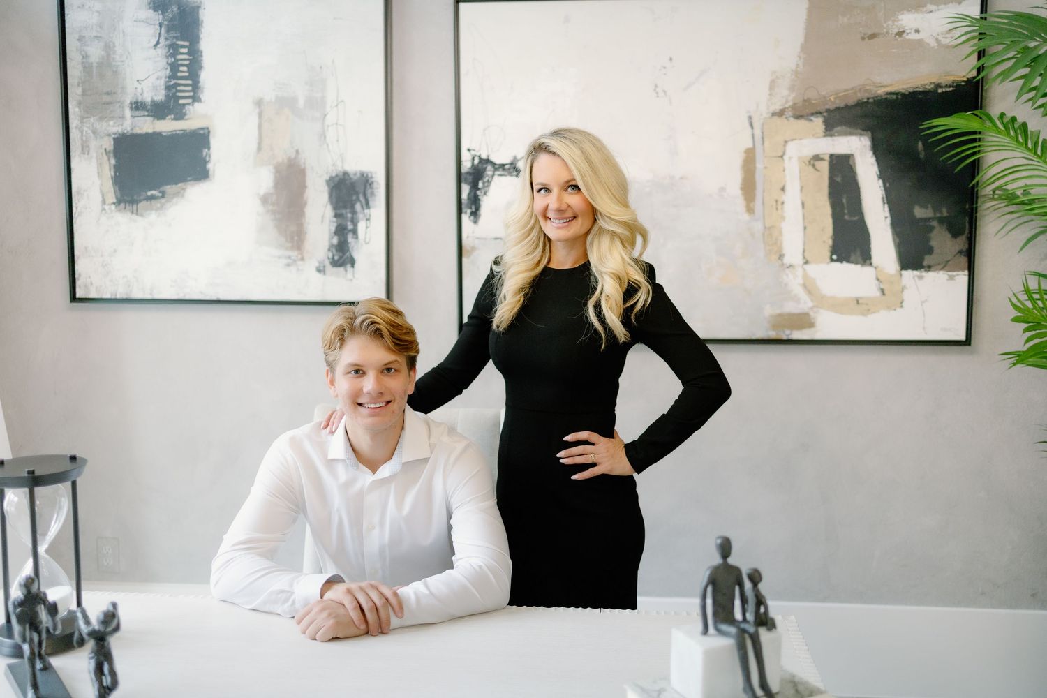 Professional business meeting between two people sitting at a desk in a modern office space with artwork on walls.