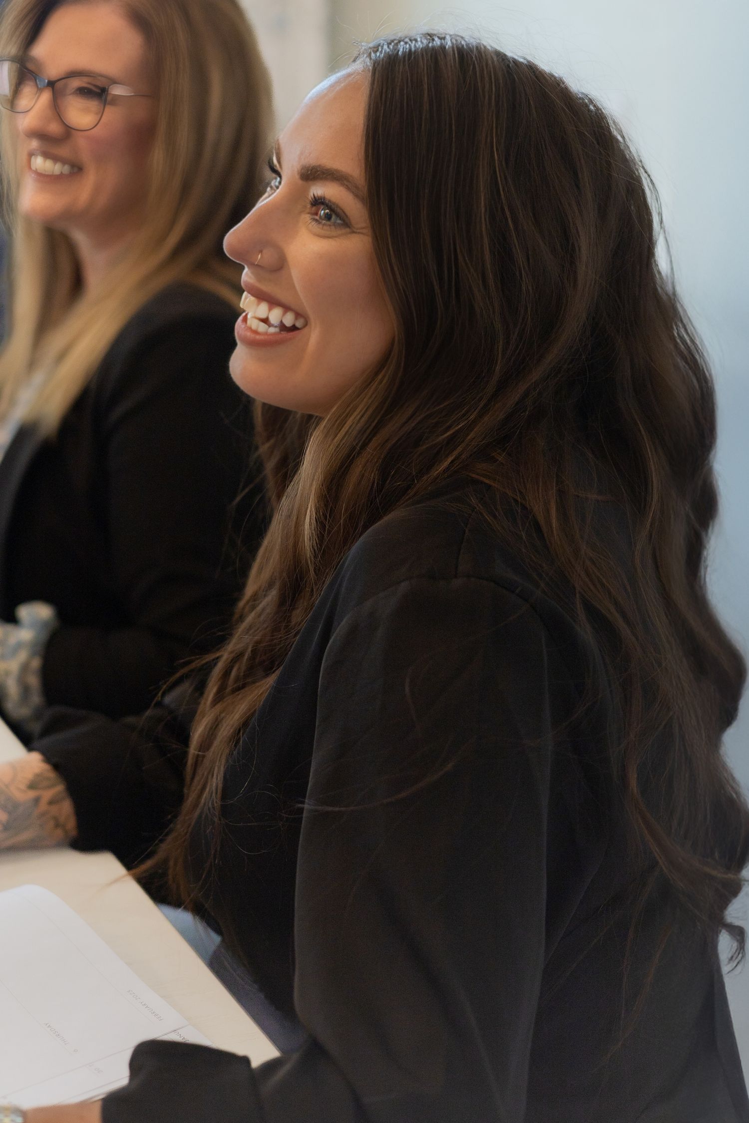 Professional in black blazer smiling during office meeting.