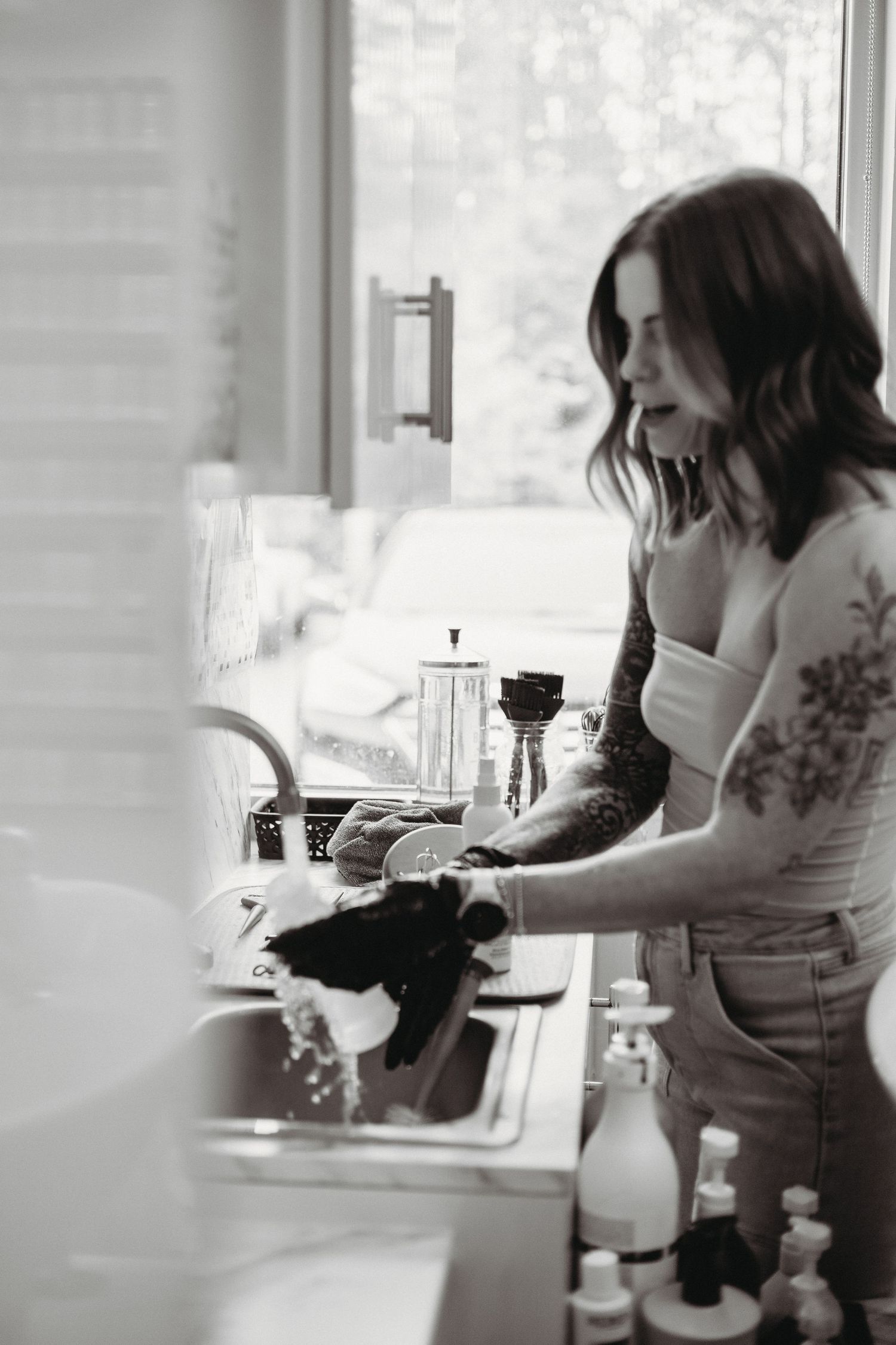 Black and white image of hair washing station with natural light from window.
