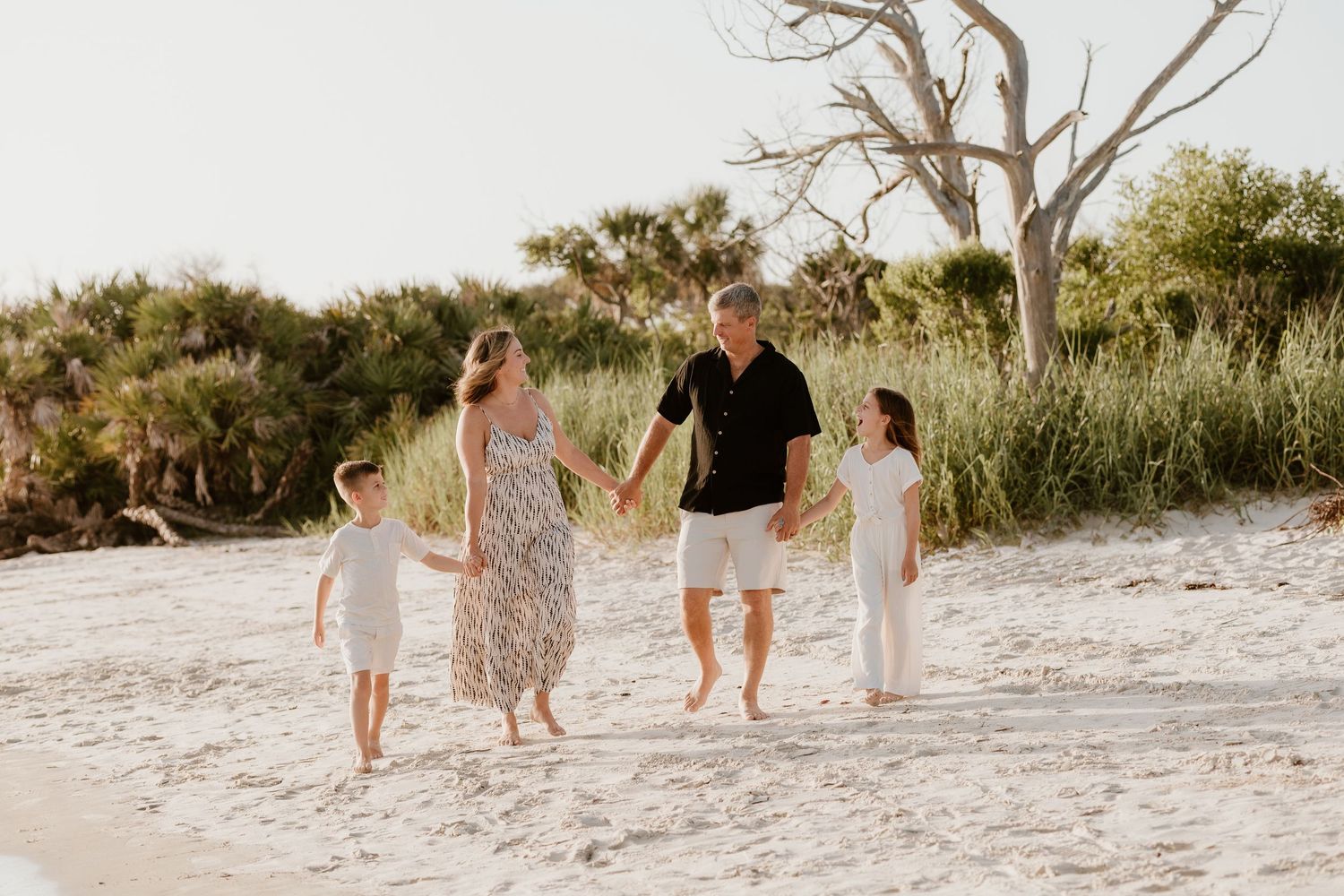 Family walking together on sandy beach at sunset.